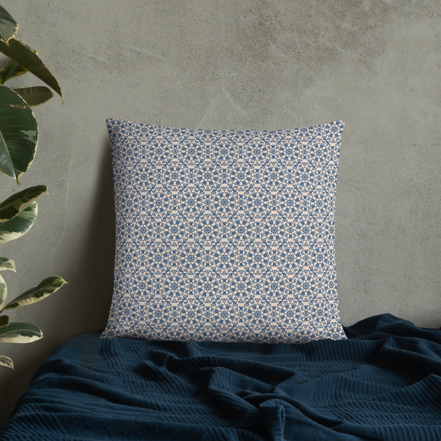 22″×22″ throw pillow with the ‘Octagon’ navy and beige geometric pattern on a bed with dark blanket.
