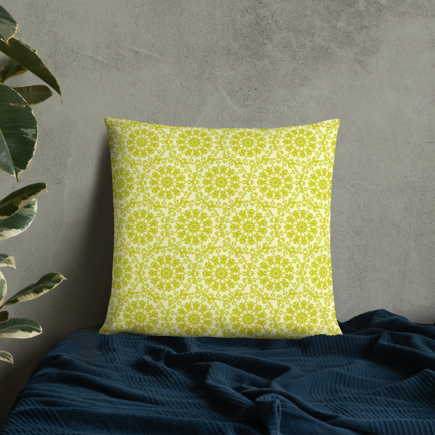 22″×22″ throw pillow with the 'Hendecagon' yellow-green geometric pattern on a bed with concrete wall