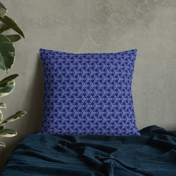 Navy and blue geometric throw pillow on a bed.
