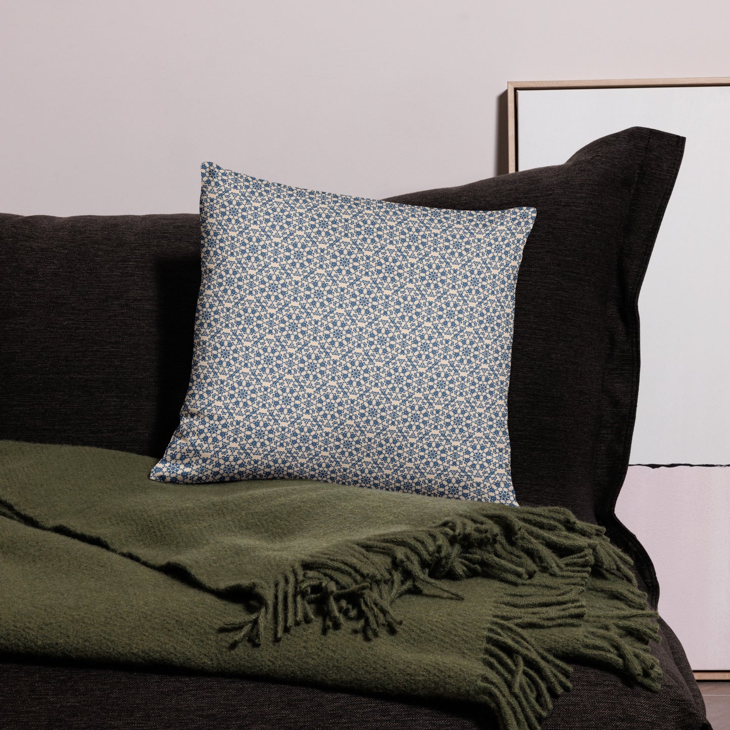 18″×18″ throw pillow with the ‘Octagon’ navy and beige geometric pattern on a dark sofa with throw blanket.