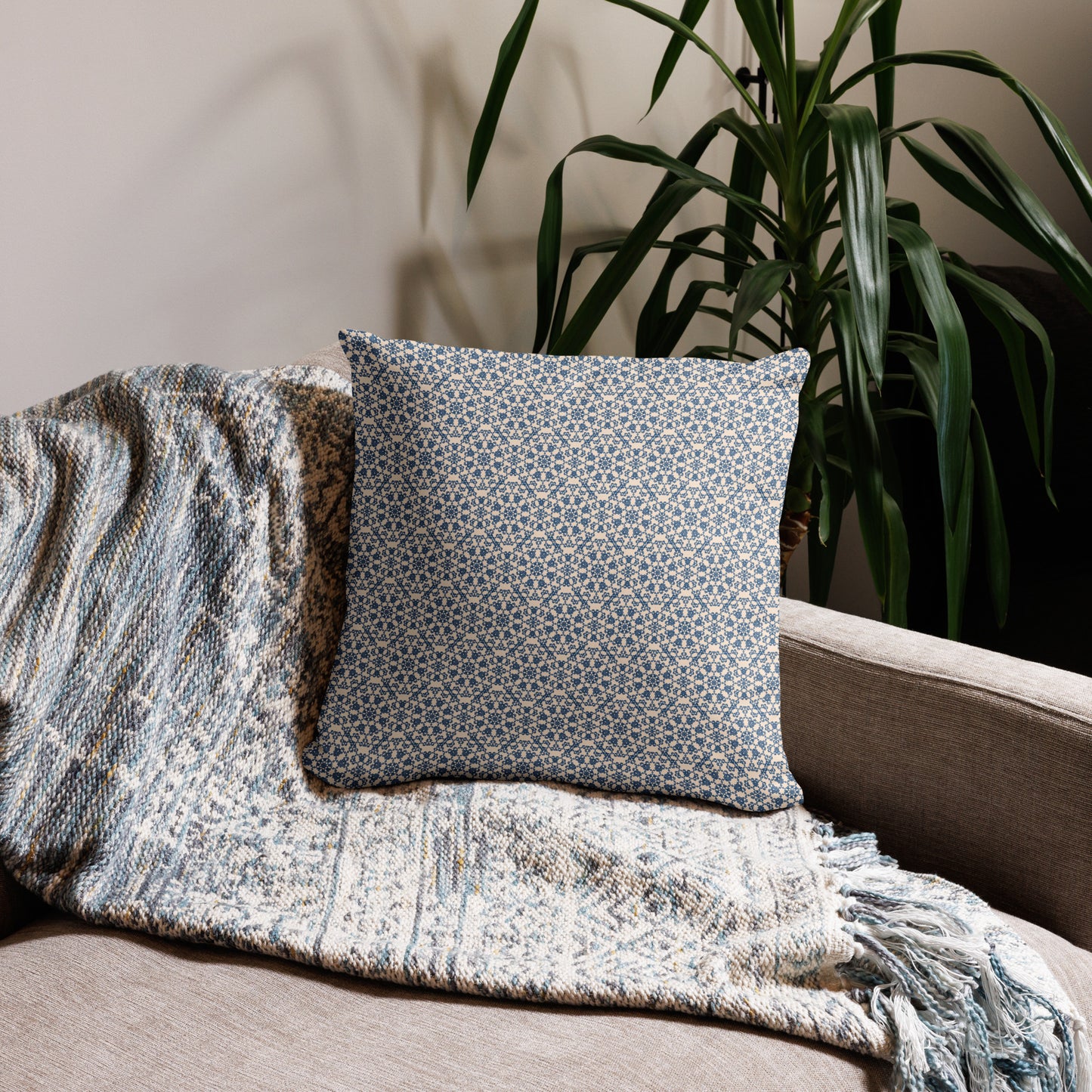 18″×18″ throw pillow with the ‘Octagon’ navy and beige geometric pattern on a sofa with fringed blanket.