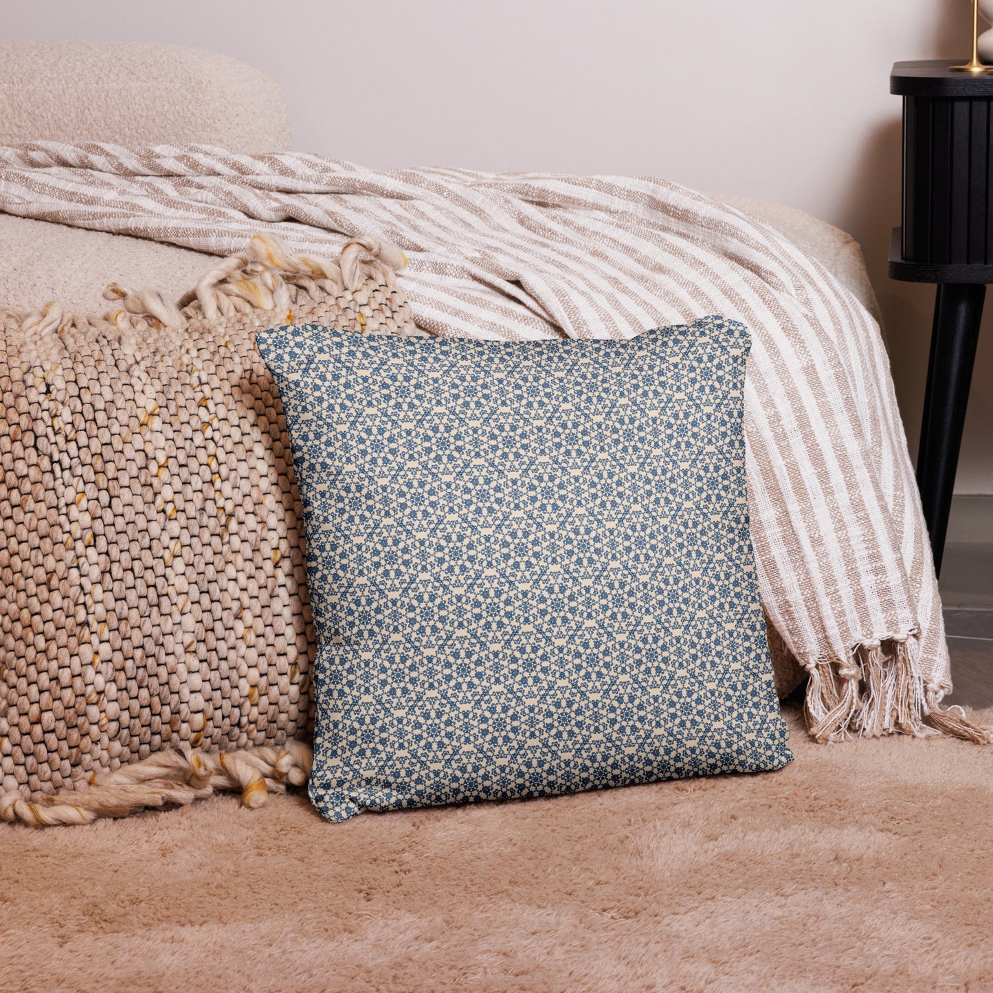18″×18″ throw pillow with the ‘Octagon’ navy and beige geometric pattern on a bed with striped blanket.