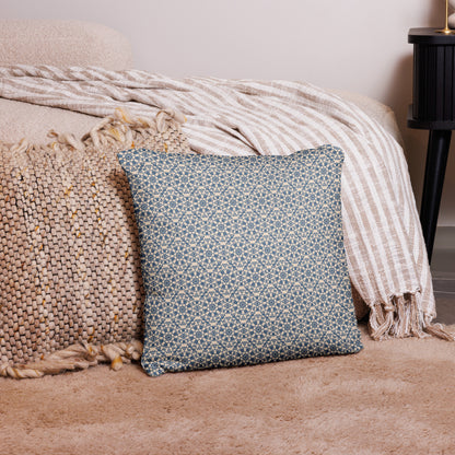 18″×18″ throw pillow with the ‘Octagon’ navy and beige geometric pattern on a bed with striped blanket.