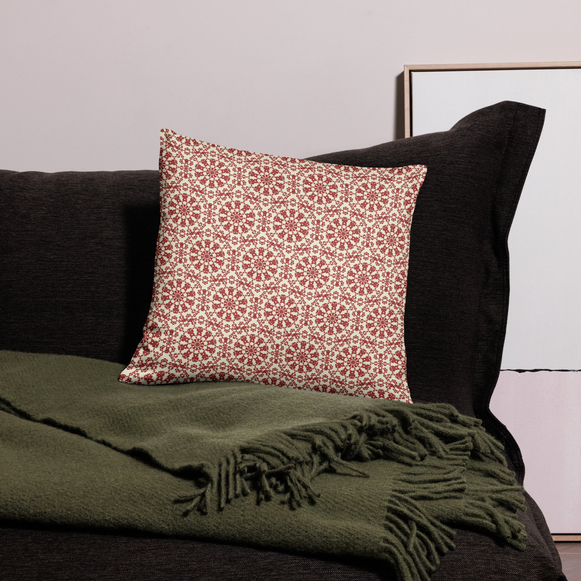 18″×18″ throw pillow with the ‘Decagon’ terracotta and beige geometric pattern on a black sofa with an olive throw.