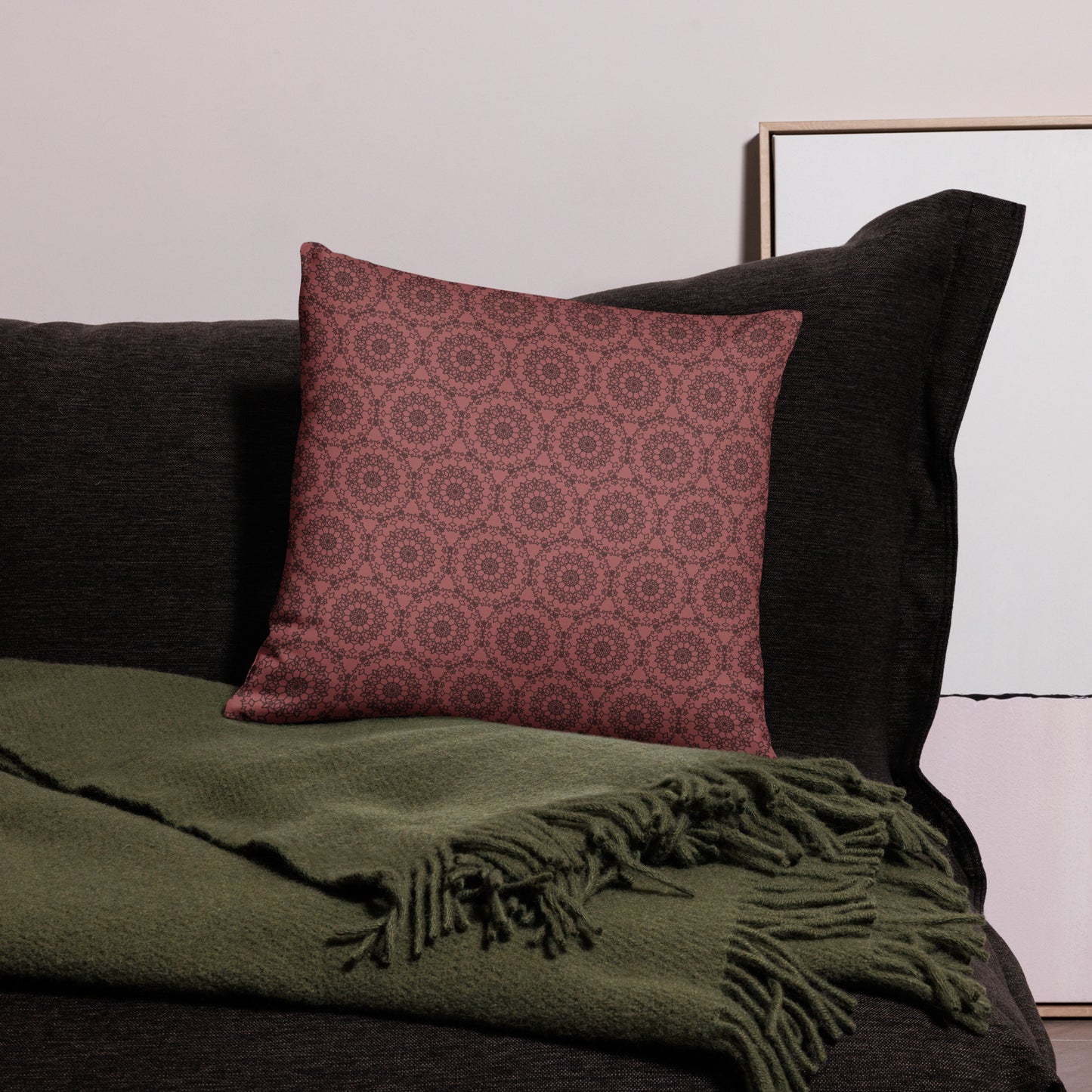 18″×18″ throw pillow with the 'Dodecagon' rose geometric pattern on dark sofa with green fringed throw.