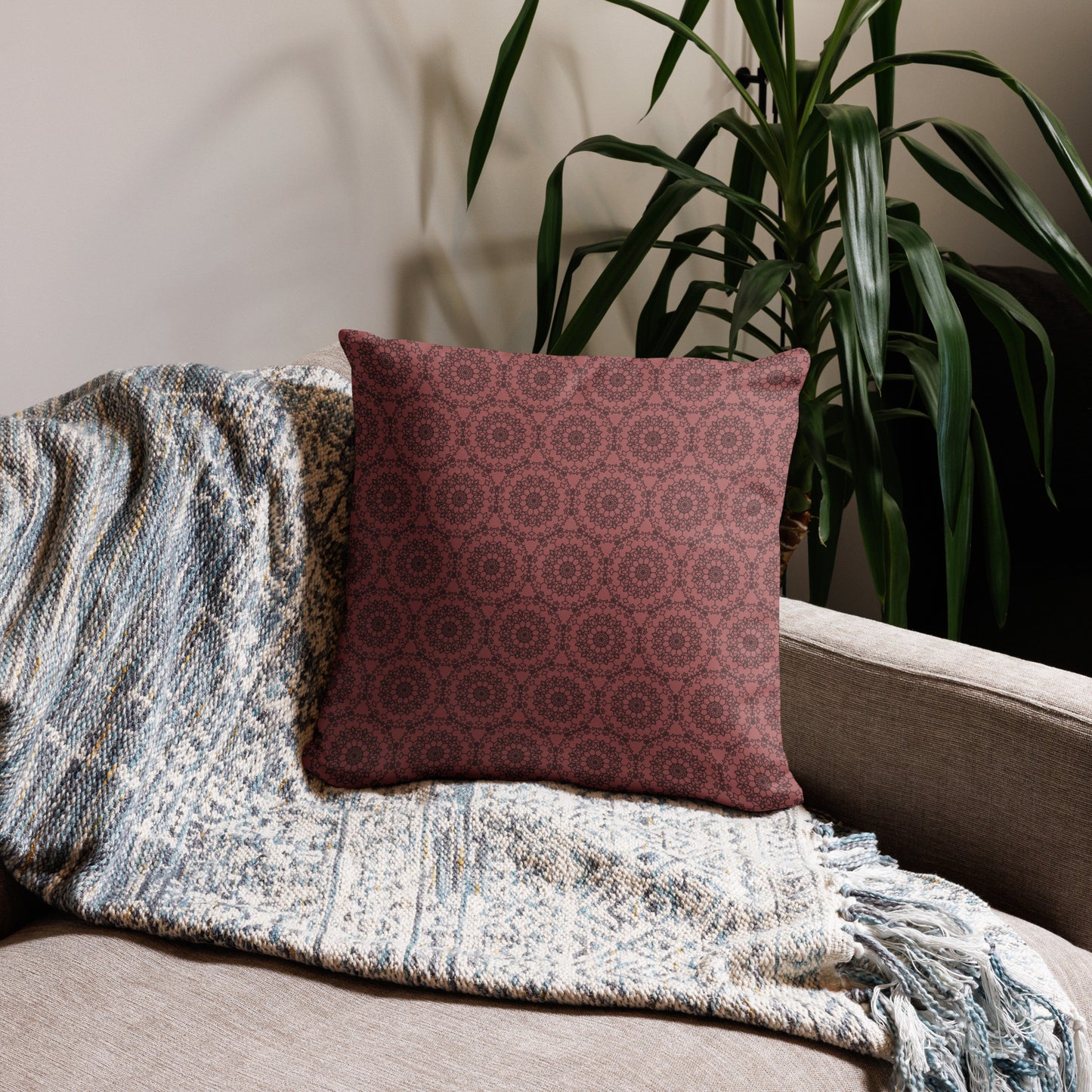 18″×18″ throw pillow with the 'Dodecagon' rose geometric pattern on beige sofa with woven throw blanket.