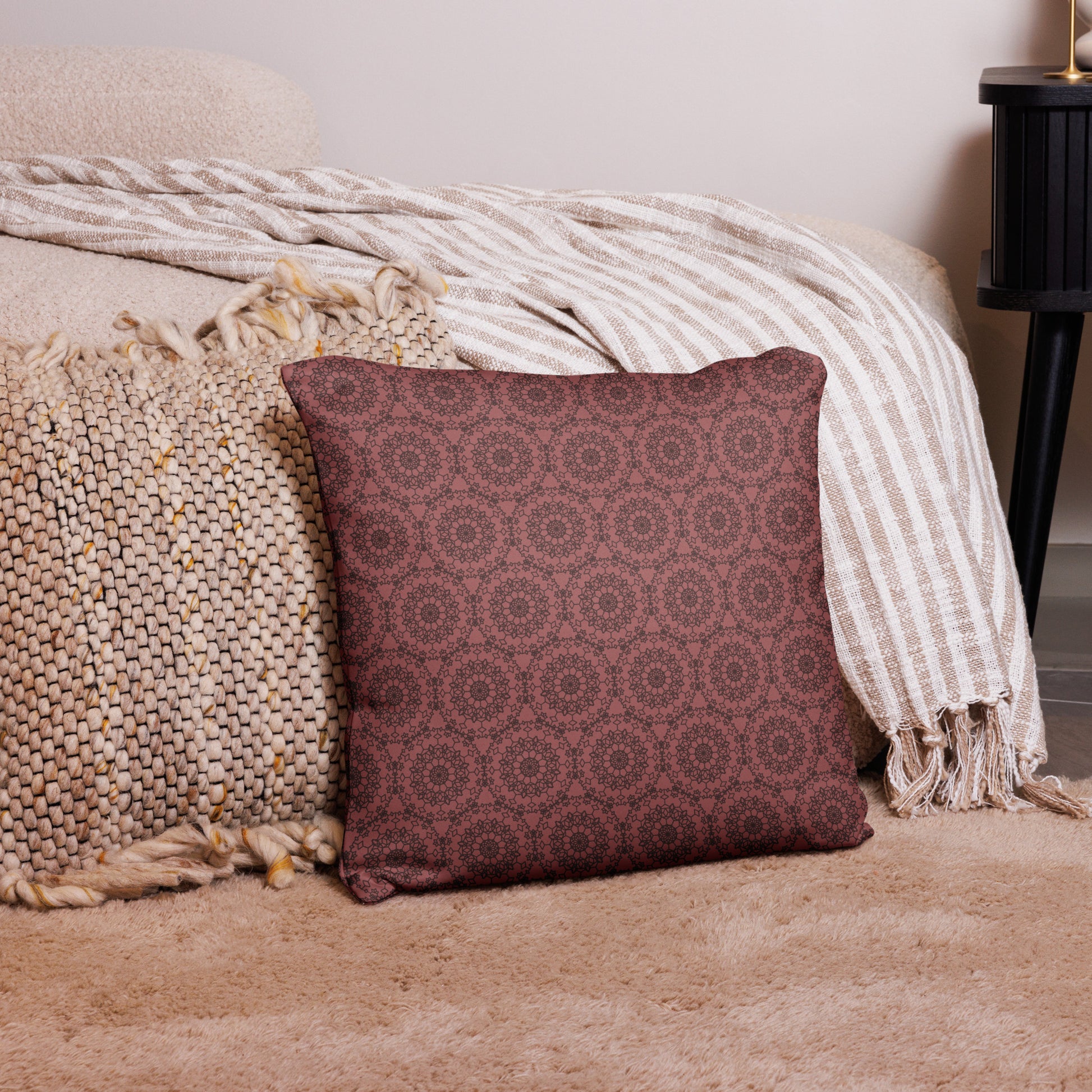 18″×18″ throw pillow with the 'Dodecagon' rose geometric pattern on carpet beside bed with striped throw.