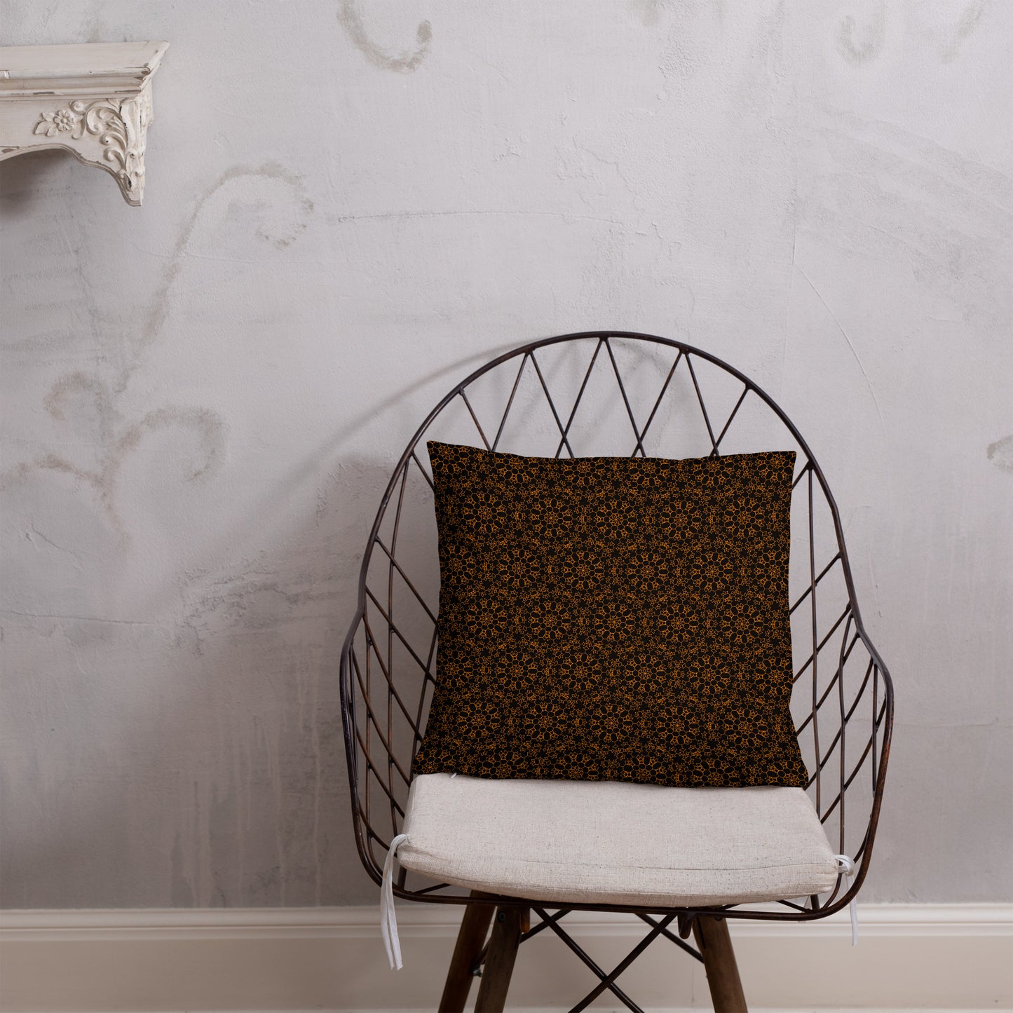 18″×18″ throw pillow with the 'Enneagon' black & gold geometric pattern on a wire chair.