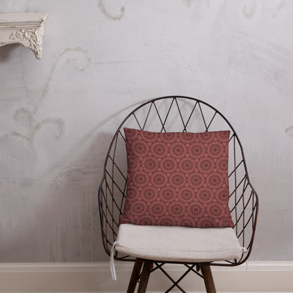 18″×18″ throw pillow with the 'Dodecagon' rose geometric pattern on wire chair with white cushion against textured wall.