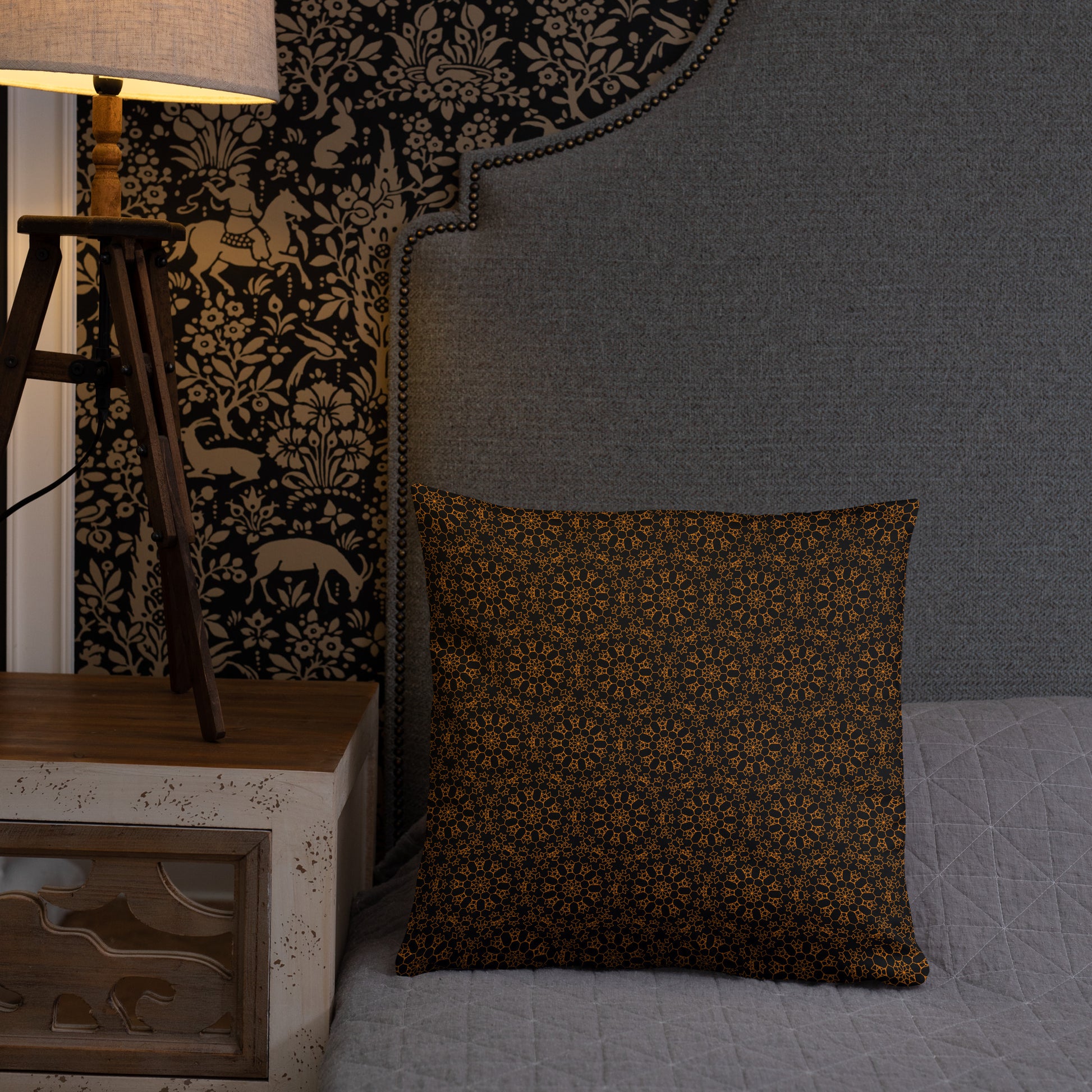 18″×18″ throw pillow with the 'Enneagon' black & gold geometric pattern on a bed with upholstered headboard.