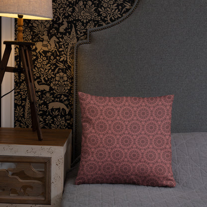 18″×18″ throw pillow with the 'Dodecagon' rose geometric pattern on bed beside grey upholstered headboard with lamp.