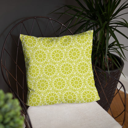 18″×18″ throw pillow with the 'Hendecagon' yellow-green geometric pattern on a wire chair with a tall potted plant