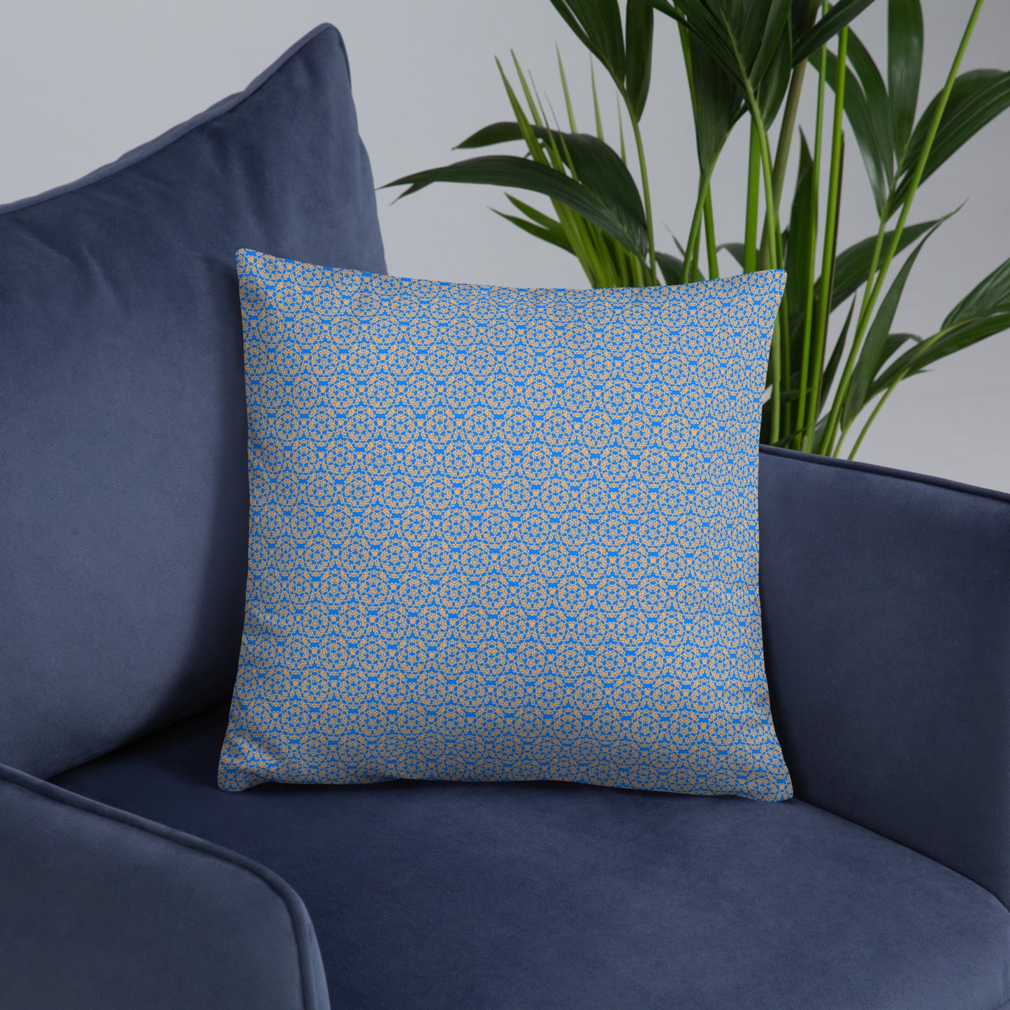 Front of the 18″×18″ basic pillow with the 'Pentagon' blue and yellow fractal geometric pattern on an armchair.