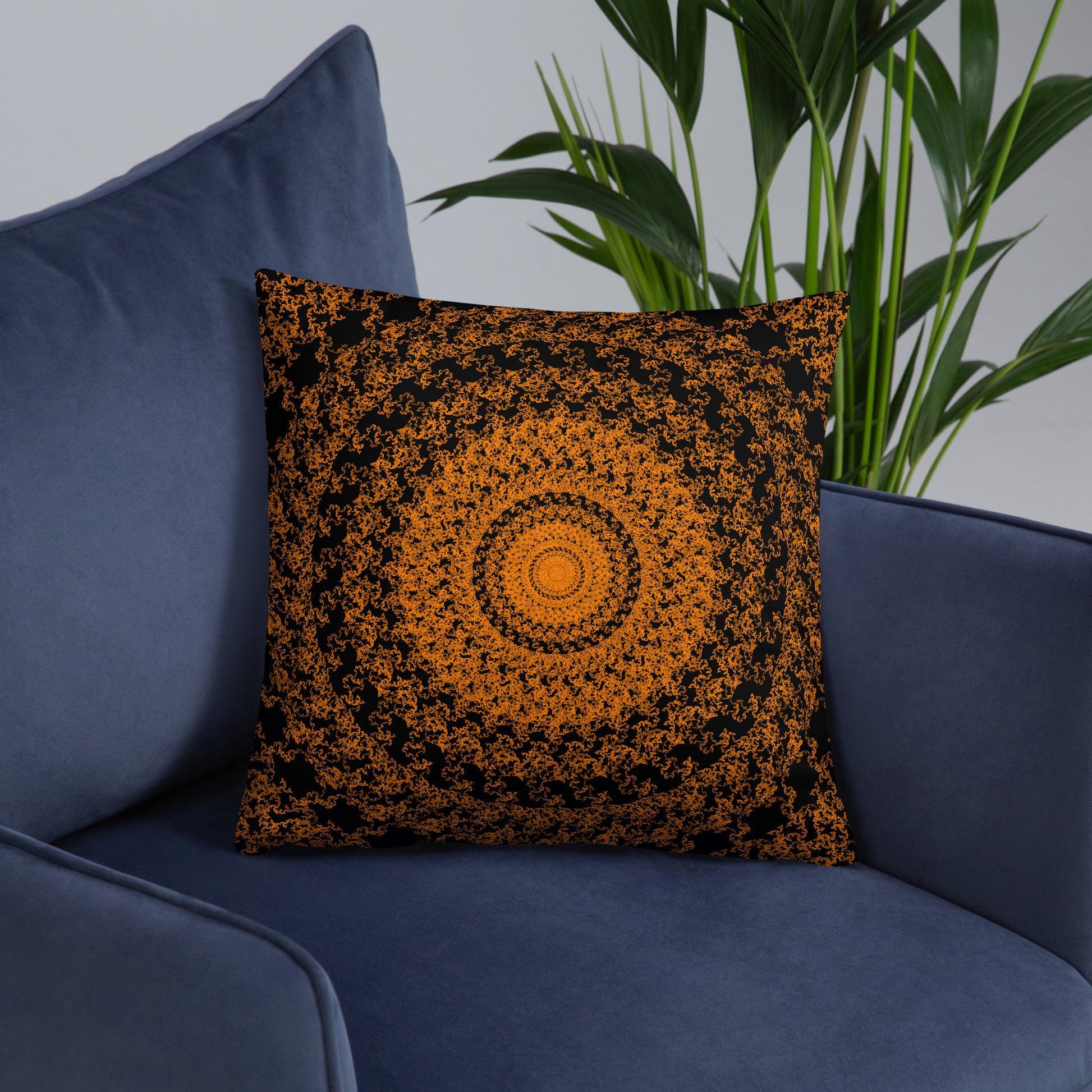 18″×18″ throw pillow with the 'The Sun' orange and black geometric design on an armchair.