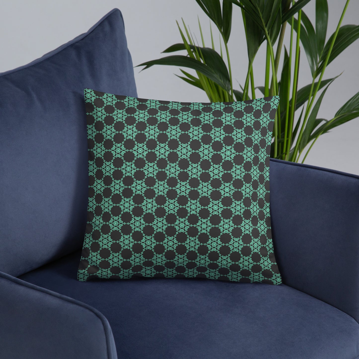 18″×18″ throw pillow with the 'Flowers Victory' charcoal and mint geometric pattern on an armchair.