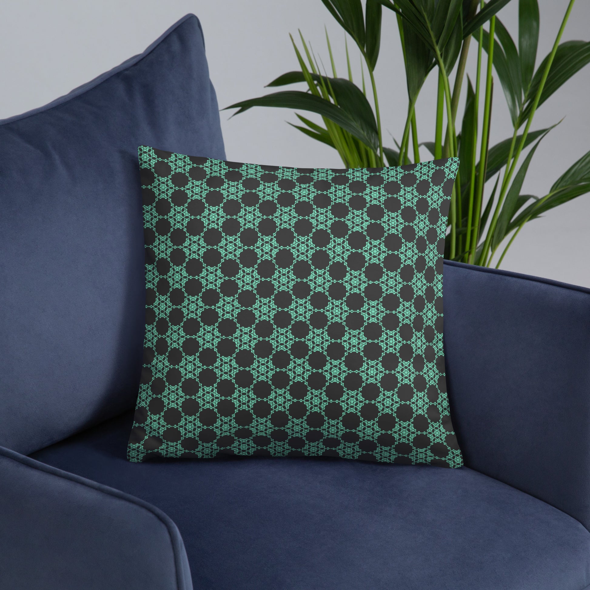 18″×18″ throw pillow with the 'Flowers Victory' charcoal and mint geometric pattern on an armchair.