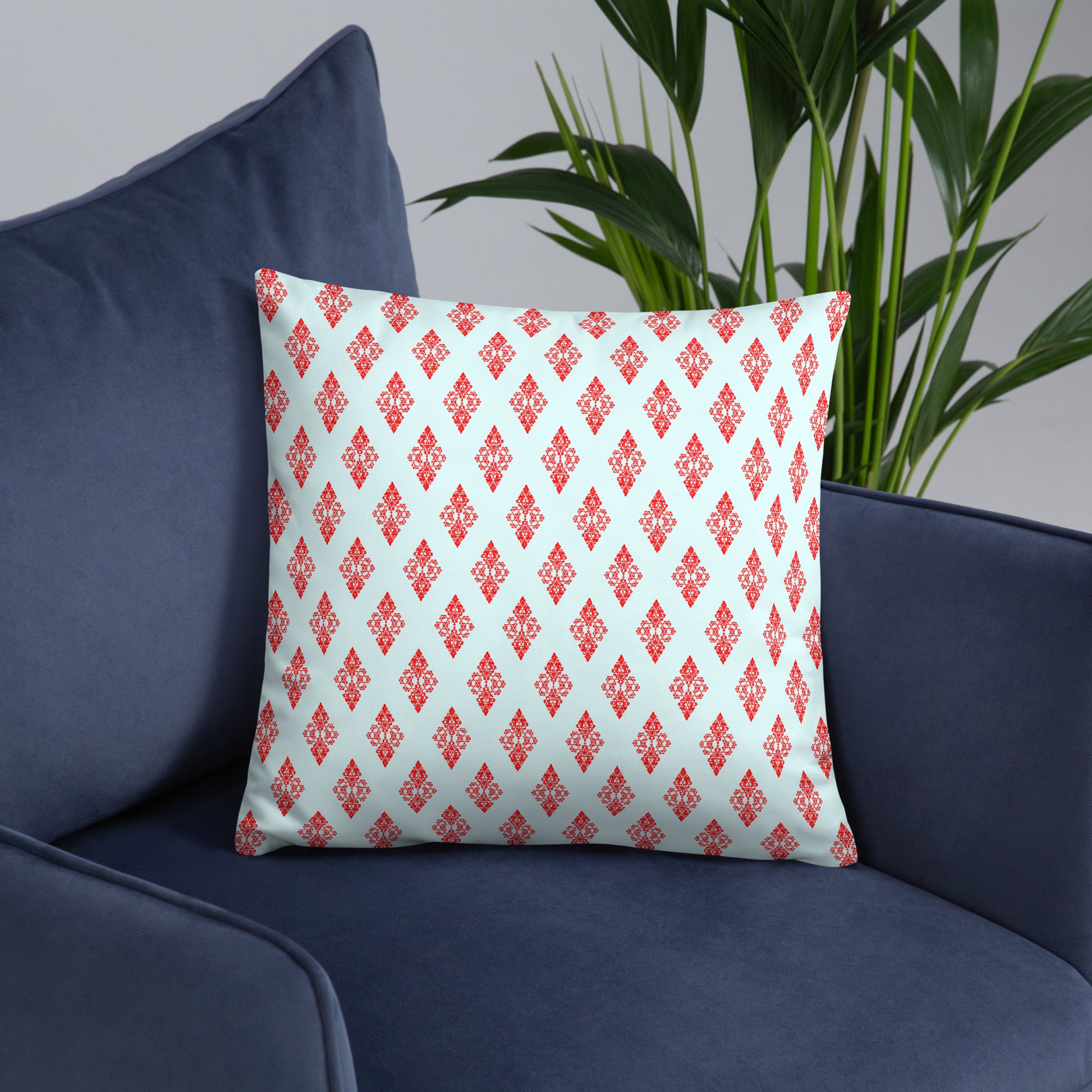 18″×18″ throw pillow with the 'Digon' sky blue and red geometric pattern on an armchair.
