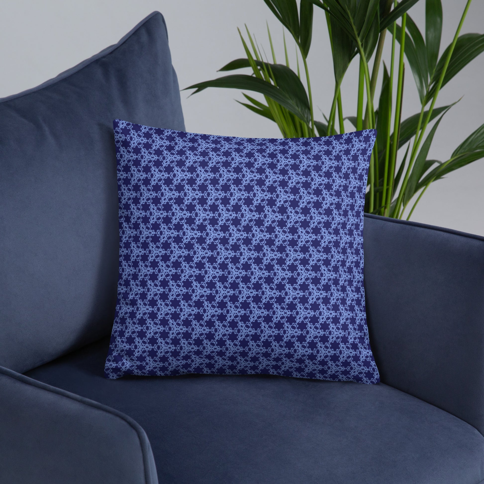 18″×18″ throw pillow with the 'Trigon' navy and blue geometric pattern on an armchair.