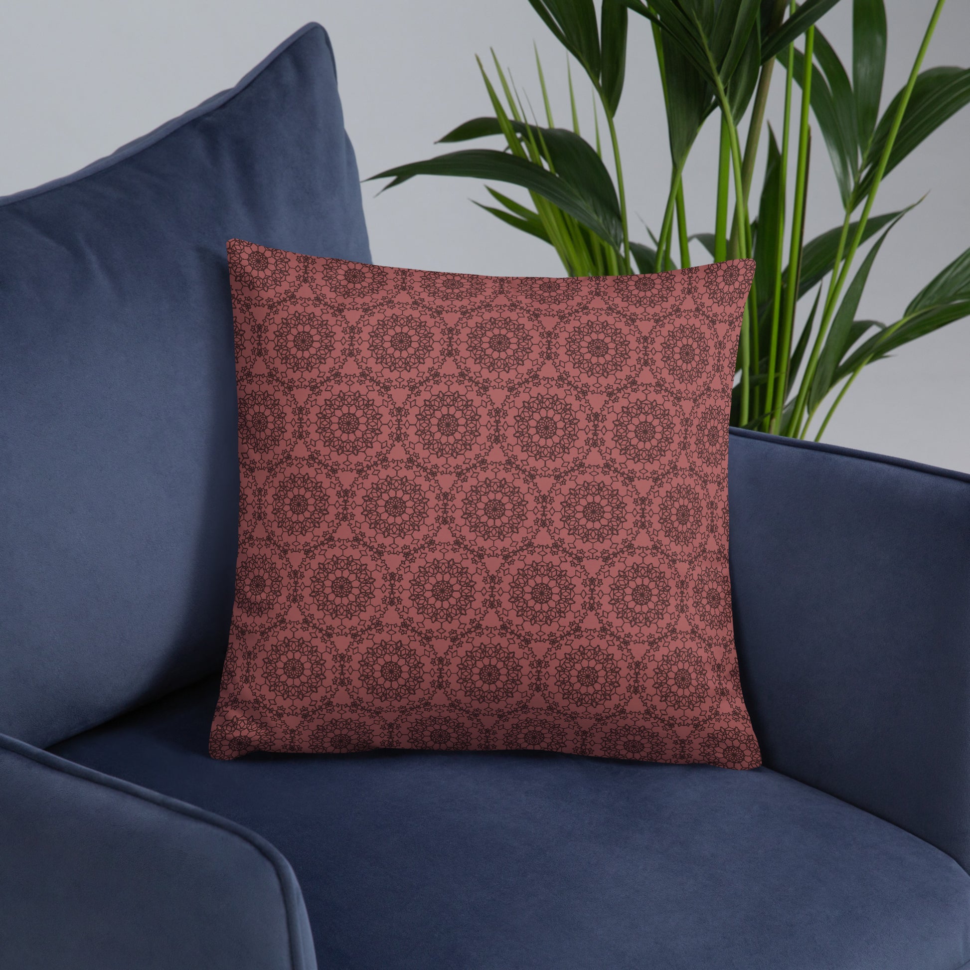 18″×18″ throw pillow with the 'Dodecagon' rose geometric pattern on navy blue armchair.