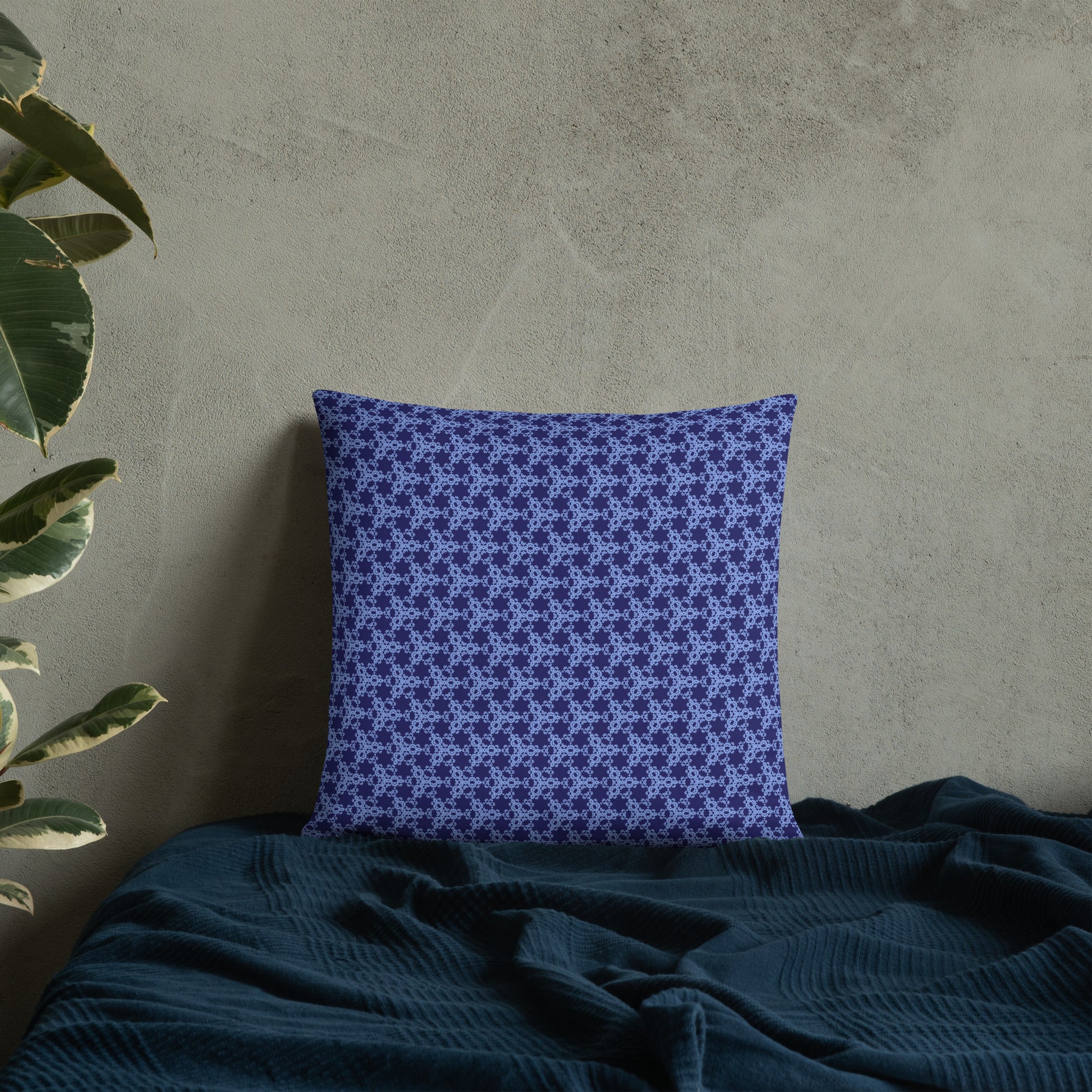 18″×18″ throw pillow with the 'Trigon' navy and blue geometric pattern on a bed.