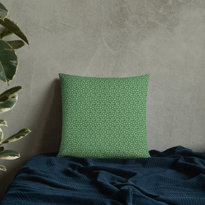 18″×18″ throw pillow with the 'Heptagon' green geometric pattern on a bed.