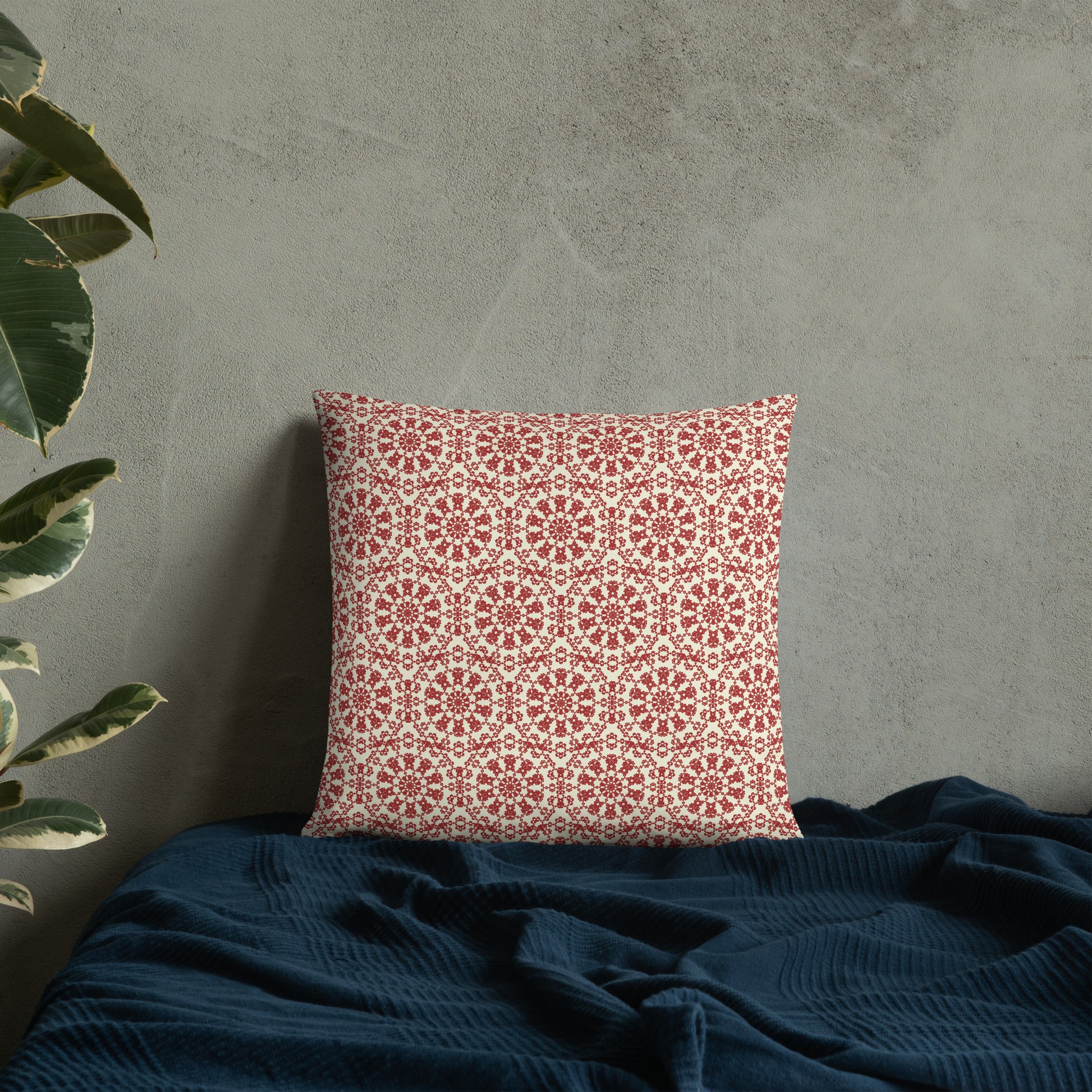 18″×18″ throw pillow with the ‘Decagon’ terracotta and beige geometric pattern on a bed with a dark navy blanket.
