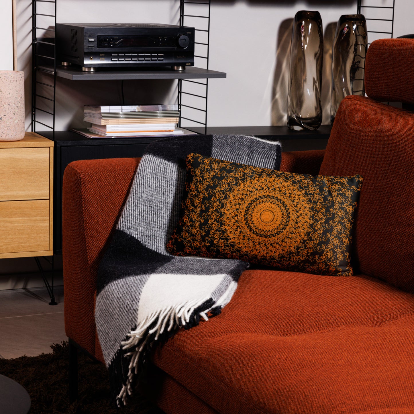 20″×12″ throw pillow with the 'The Sun' orange and black geometric design on a couch.