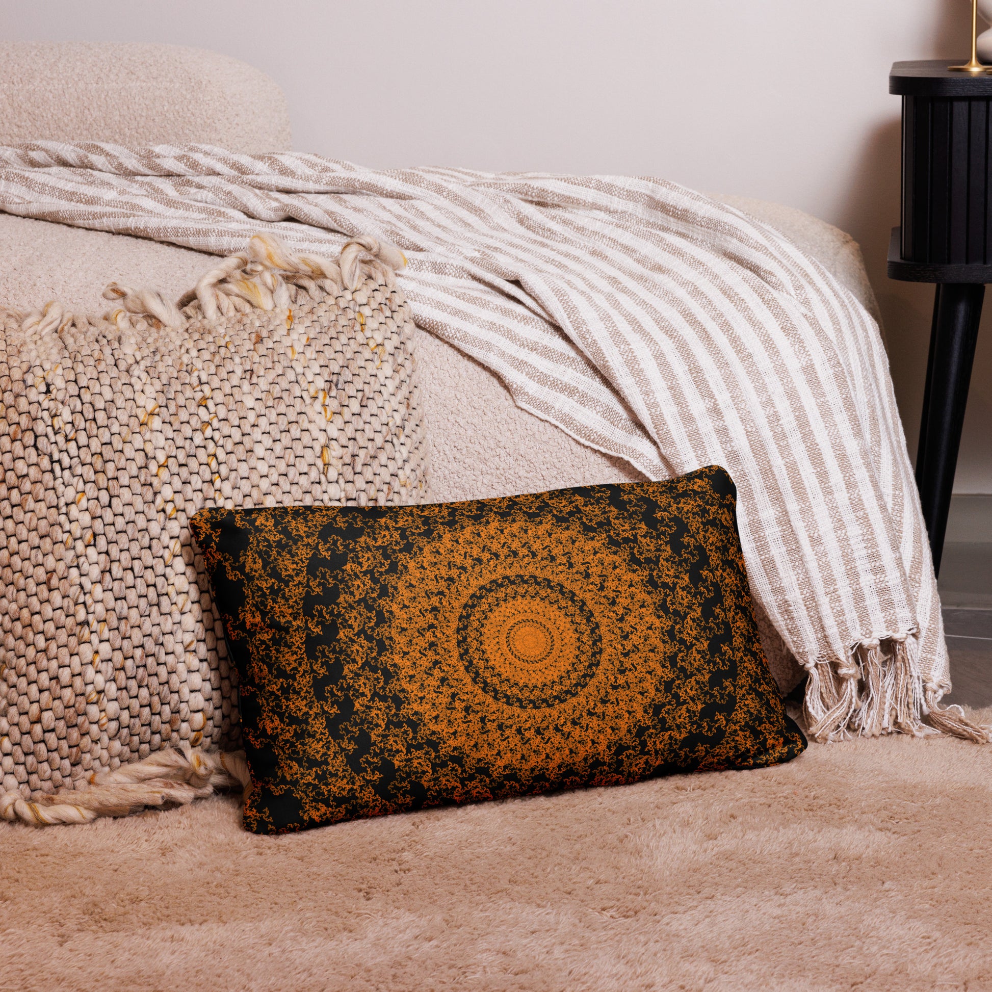 20″×12″ throw pillow with the 'The Sun' orange and black geometric design on a couch.