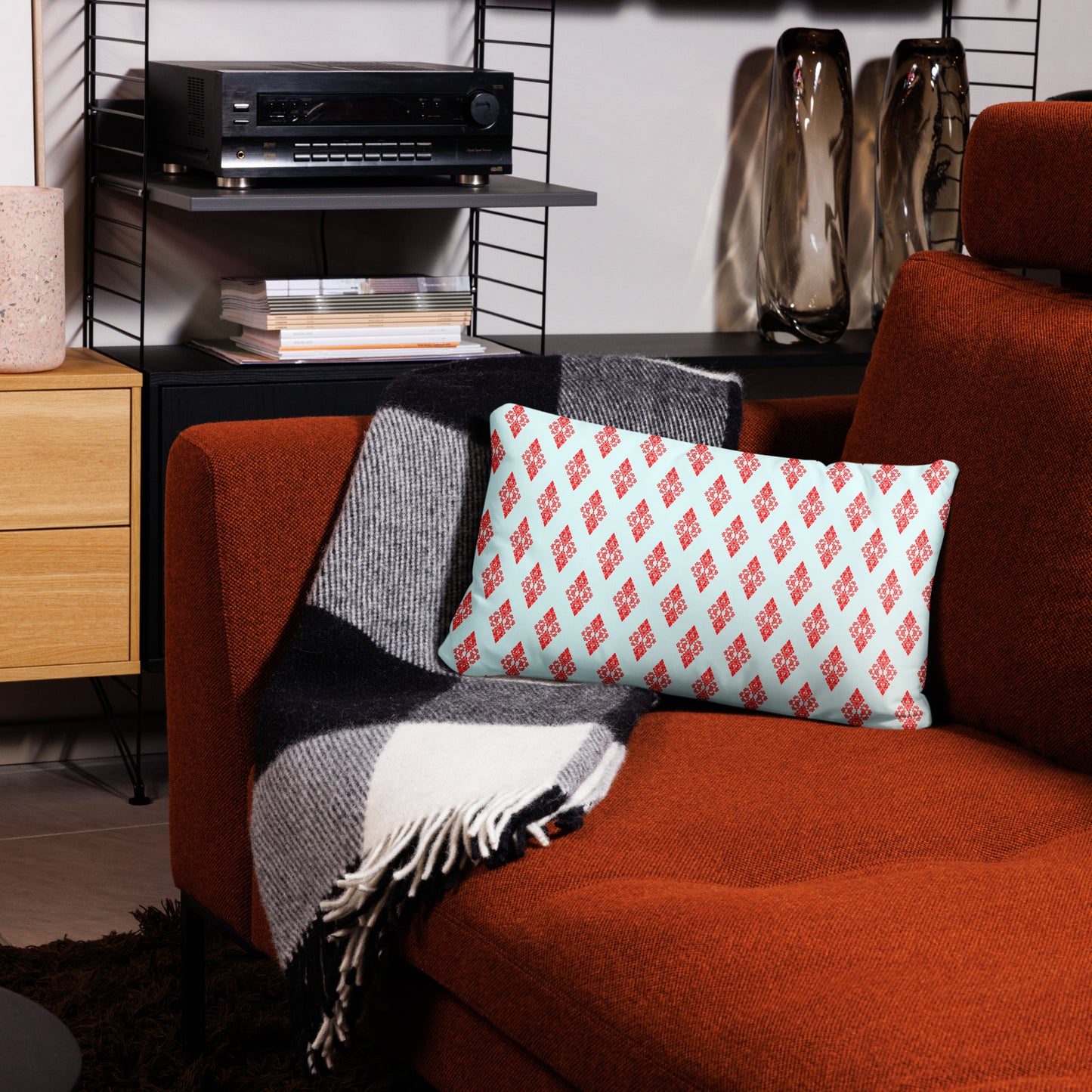 20″×12″ throw pillow with the 'Digon' sky blue and red geometric pattern on a couch.