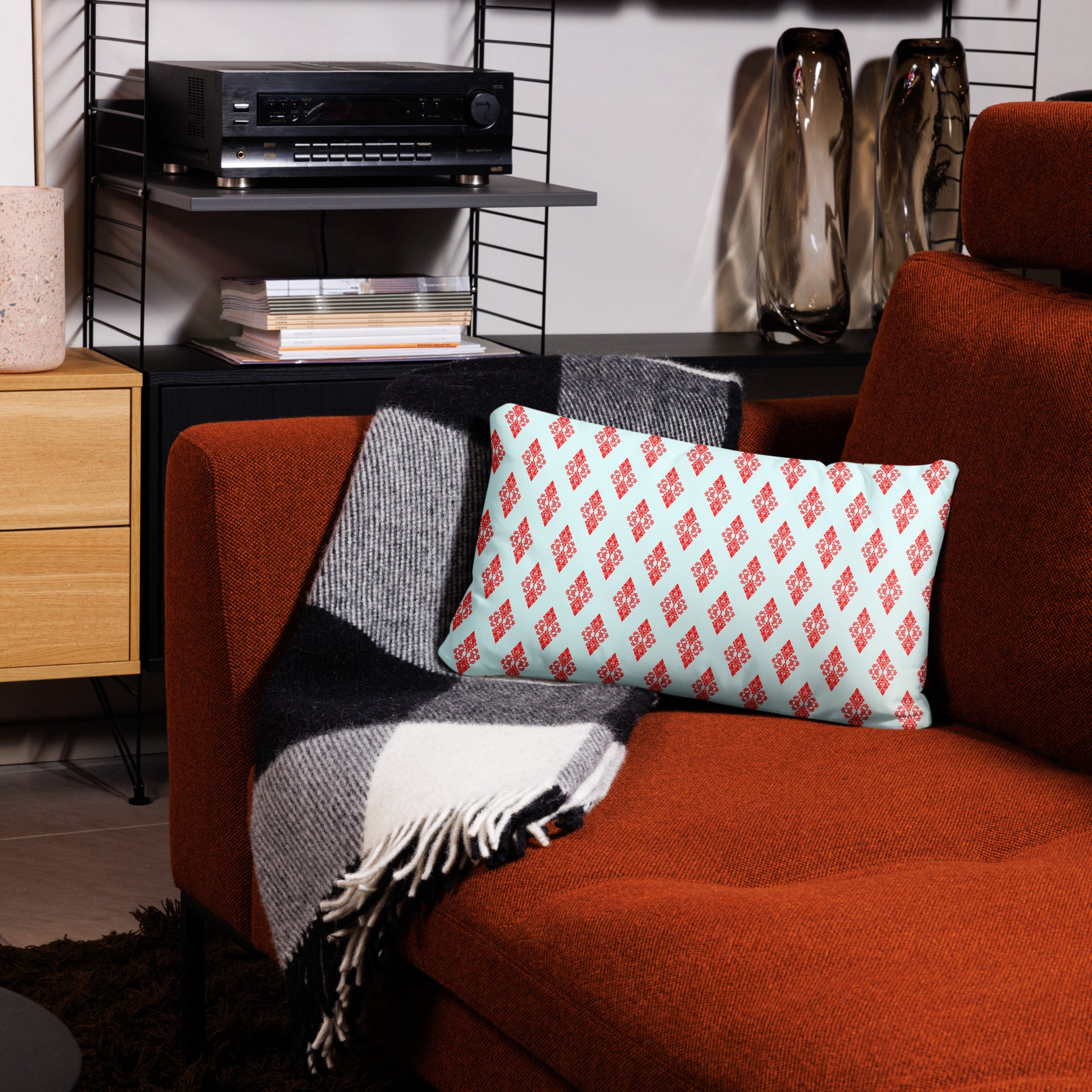 20″×12″ throw pillow with the 'Digon' sky blue and red geometric pattern on a couch.