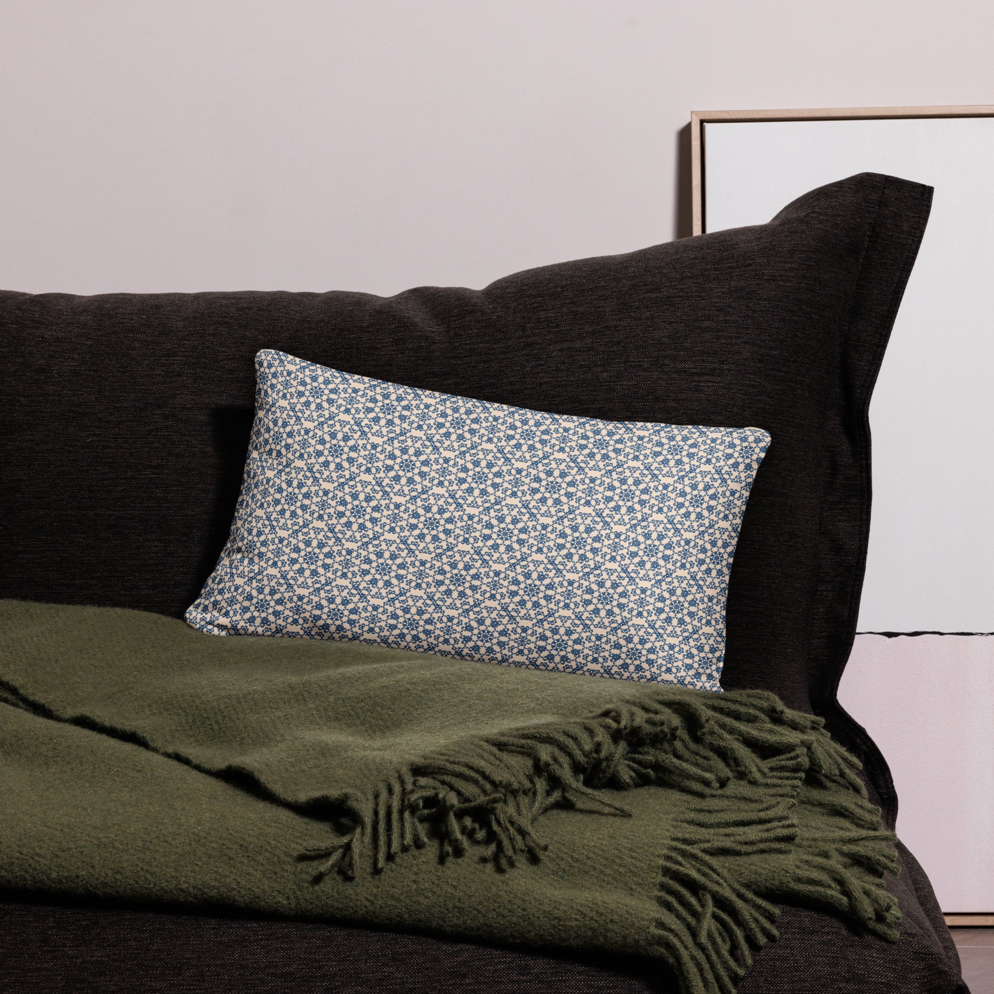 20″×12″ throw pillow with the ‘Octagon’ navy and beige geometric pattern on a dark sofa with throw blanket.