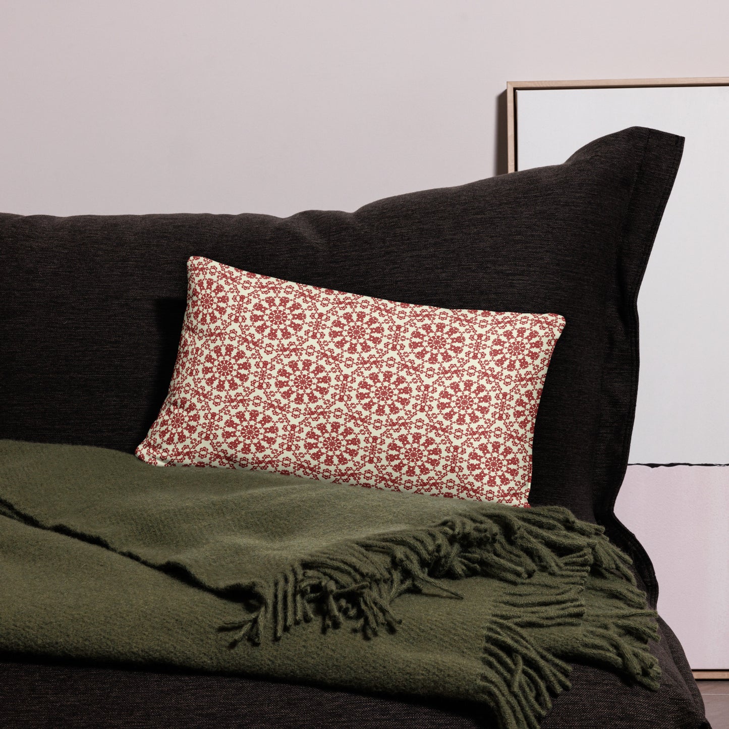 20″×12″ throw pillow with the ‘Decagon’ terracotta and beige geometric pattern on a black sofa with an olive throw.