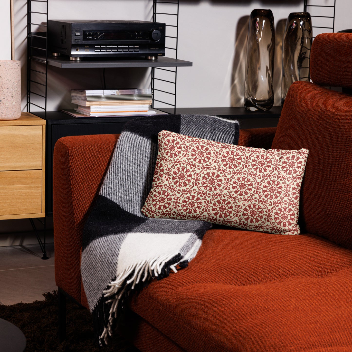 20″×12″ throw pillow with the ‘Decagon’ terracotta and beige geometric pattern on a terracotta sofa with a black and white throw.