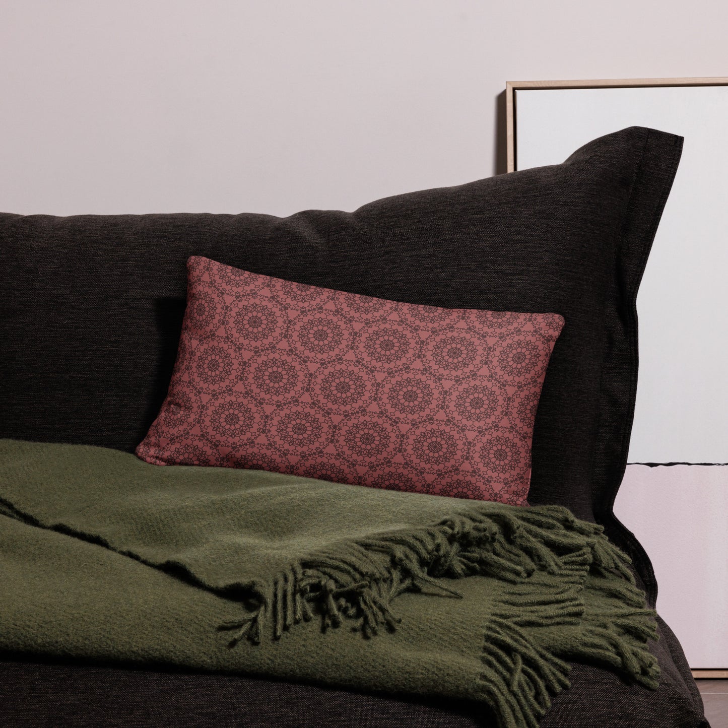 20″×12″ throw pillow with the 'Dodecagon' rose geometric pattern on dark sofa with green fringed throw.