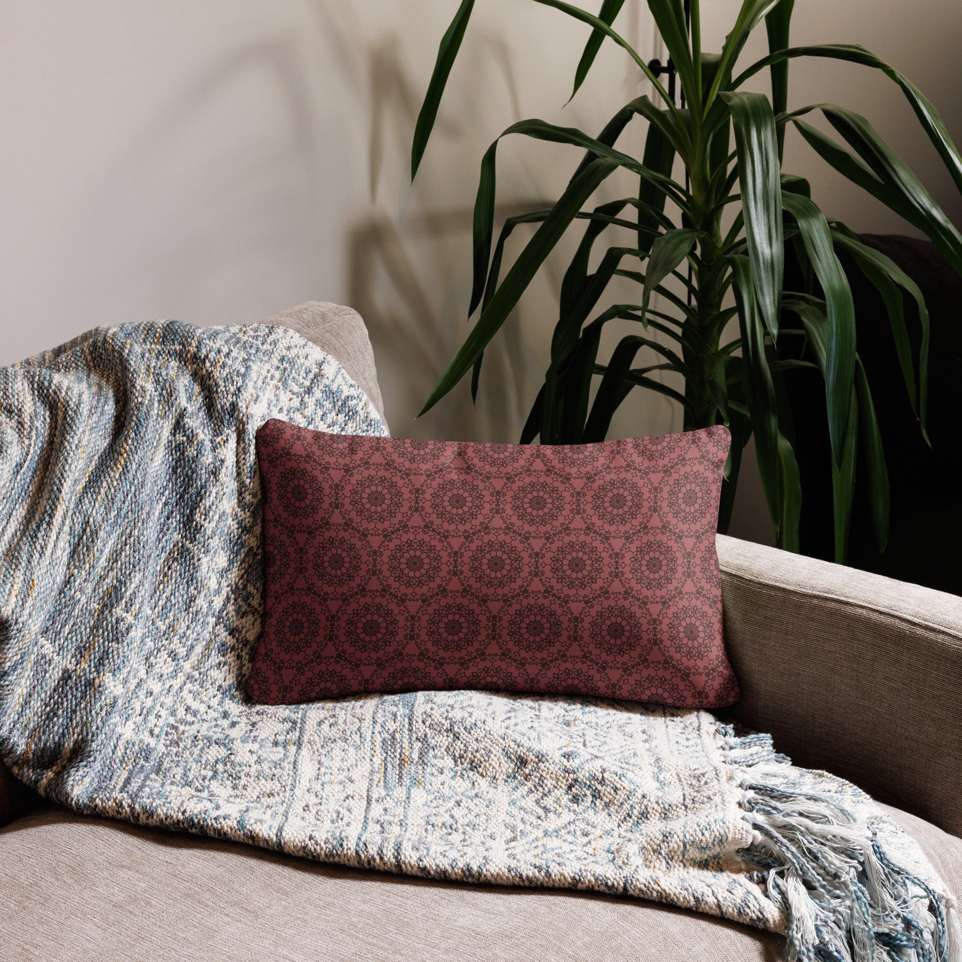 20″×12″ throw pillow with the 'Dodecagon' rose geometric pattern on beige sofa with woven throw blanket.