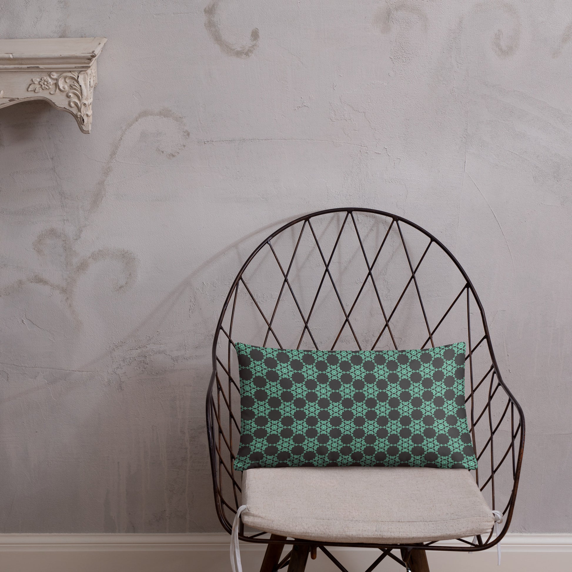 20″×12″ throw pillow with the 'Flowers Victory' charcoal and mint geometric pattern on a chair.