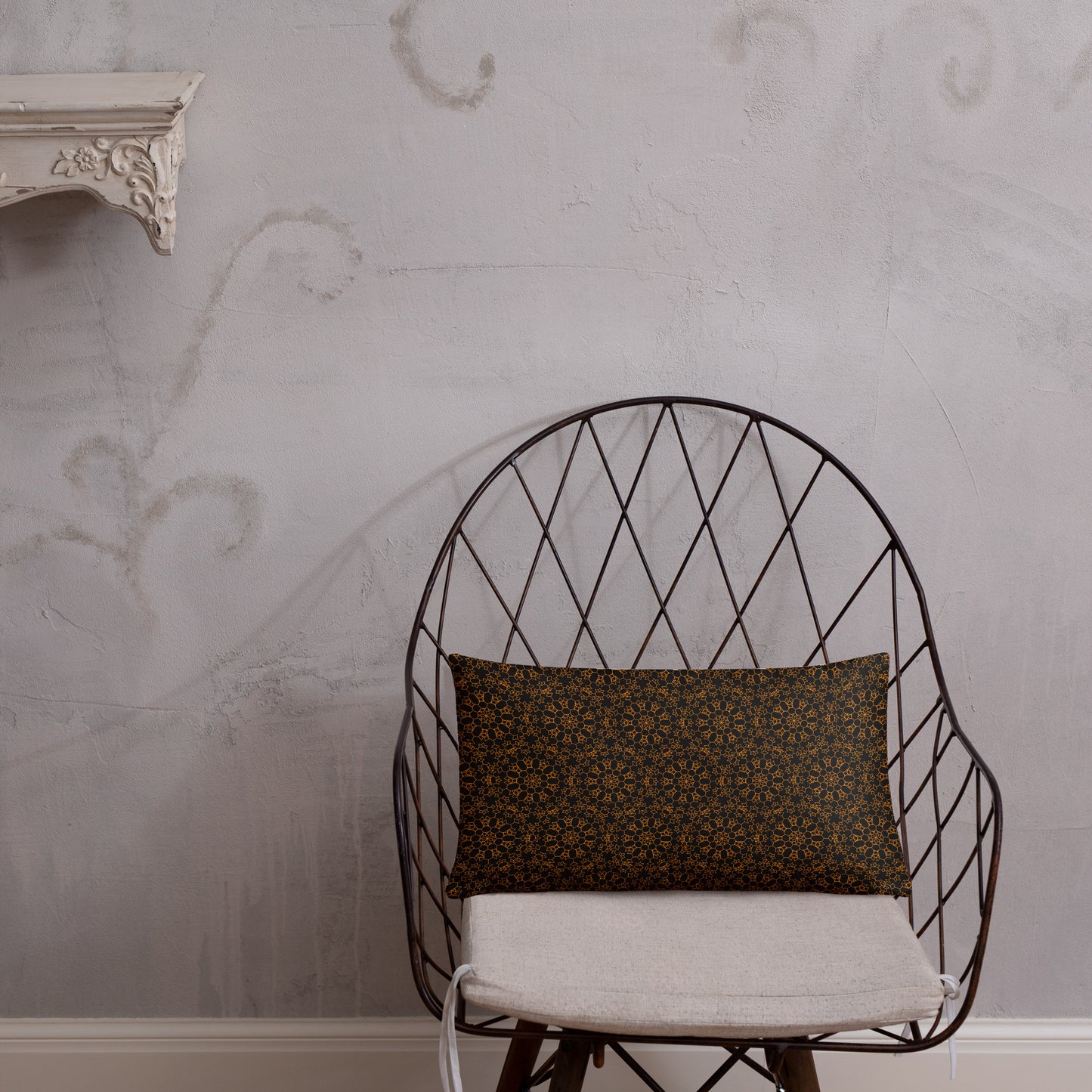 20″×12″ throw pillow with the 'Enneagon' black & gold geometric pattern on a wire chair.