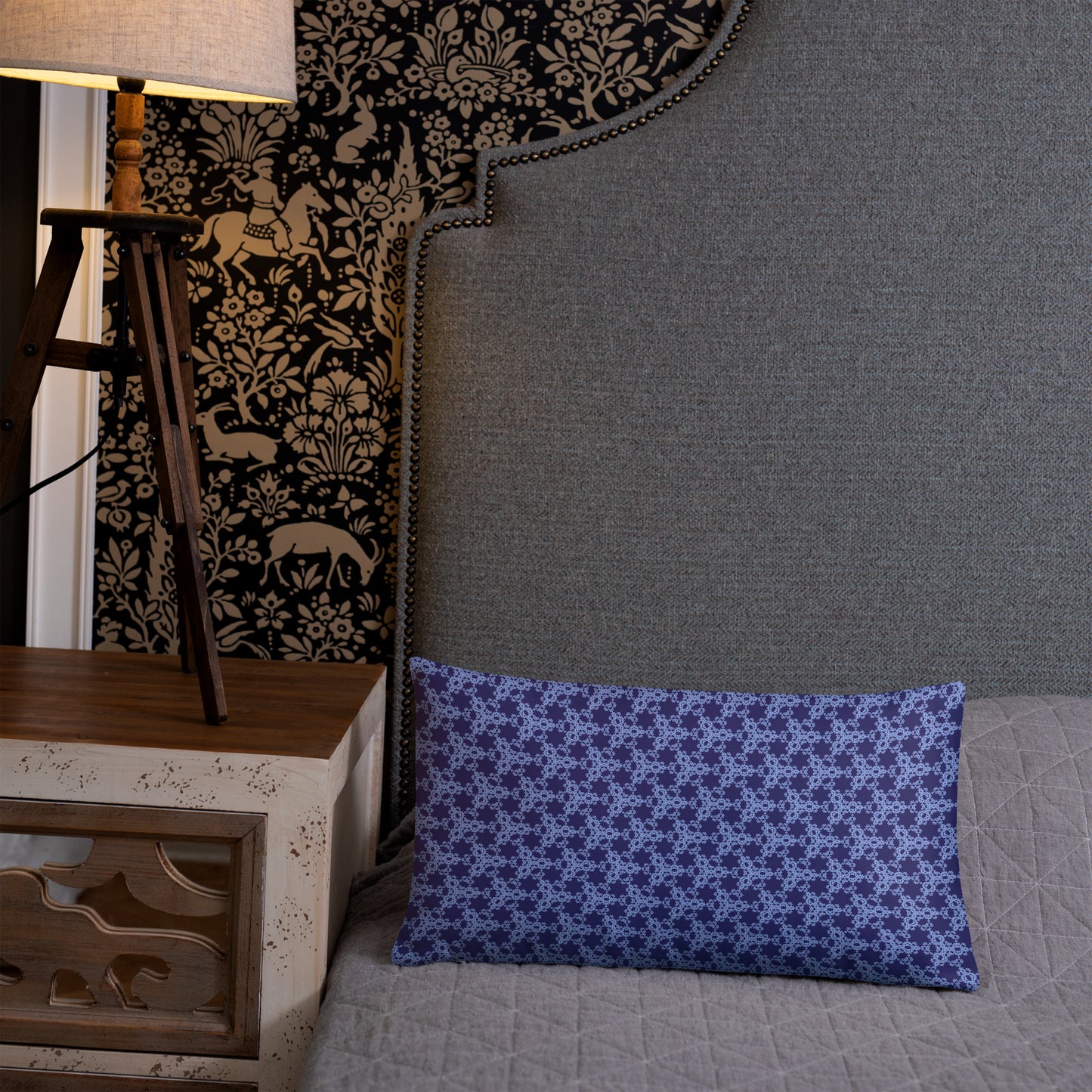 20″×12″ throw pillow with the 'Trigon' navy and blue geometric pattern on a bed.
