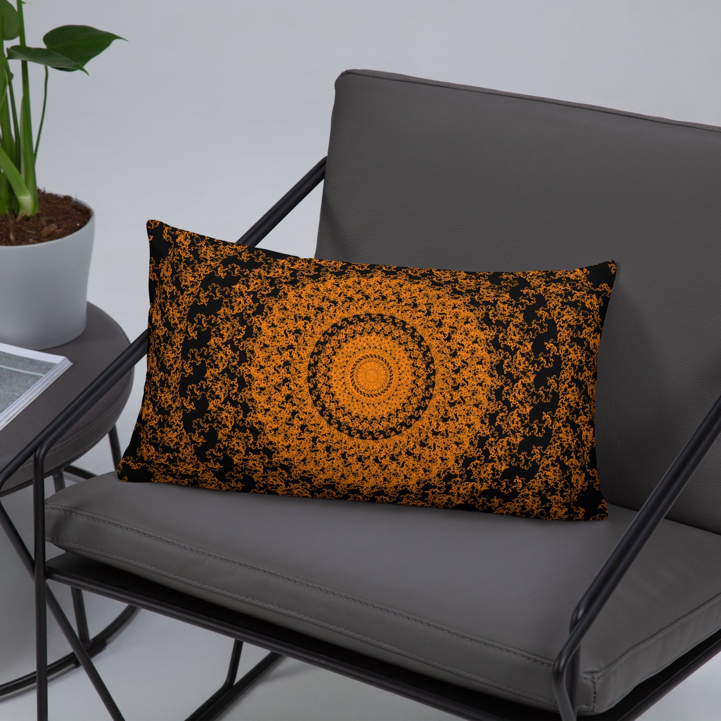 20″×12″ throw pillow with the 'The Sun' orange and black geometric design on a chair.