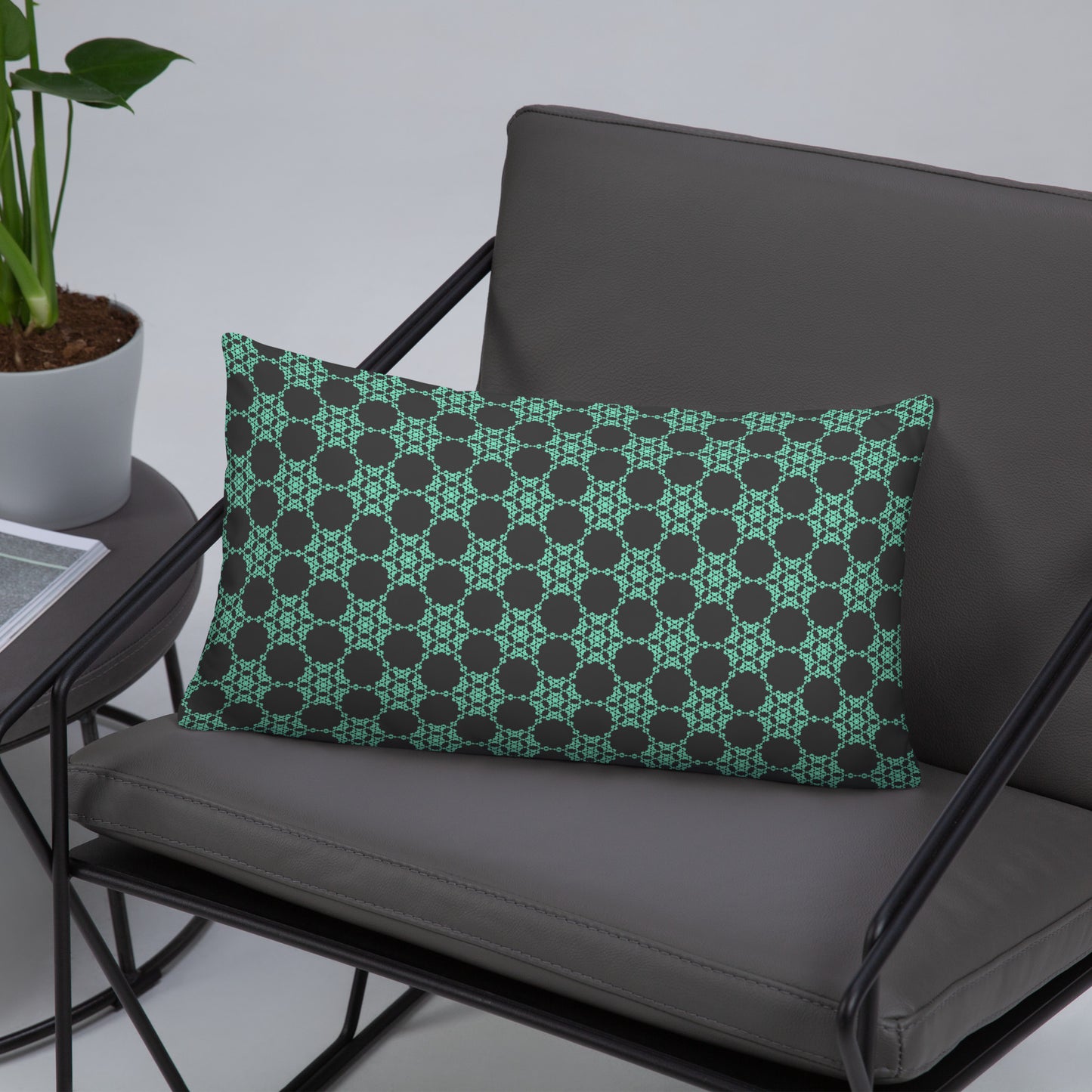 20″×12″ throw pillow with the 'Flowers Victory' charcoal and mint geometric pattern on a chair.