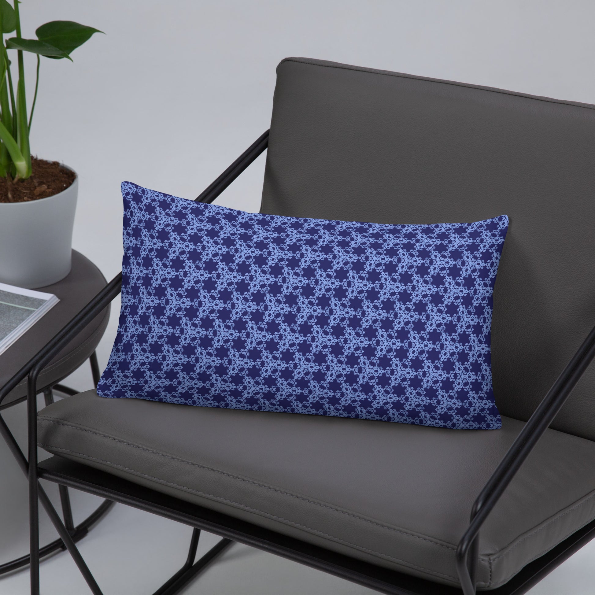 20″×12″ throw pillow with the 'Trigon' navy and blue geometric pattern on a chair.