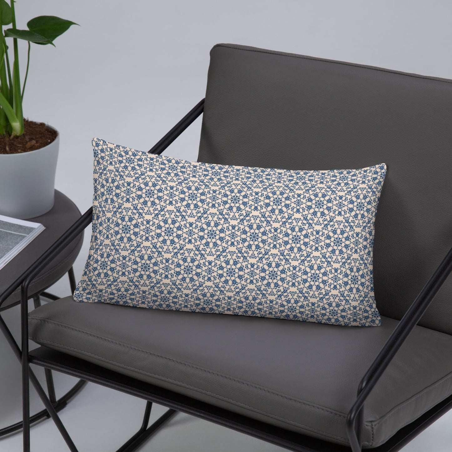 20″×12″ throw pillow with the ‘Octagon’ navy and beige geometric pattern on a gray chair with side table.