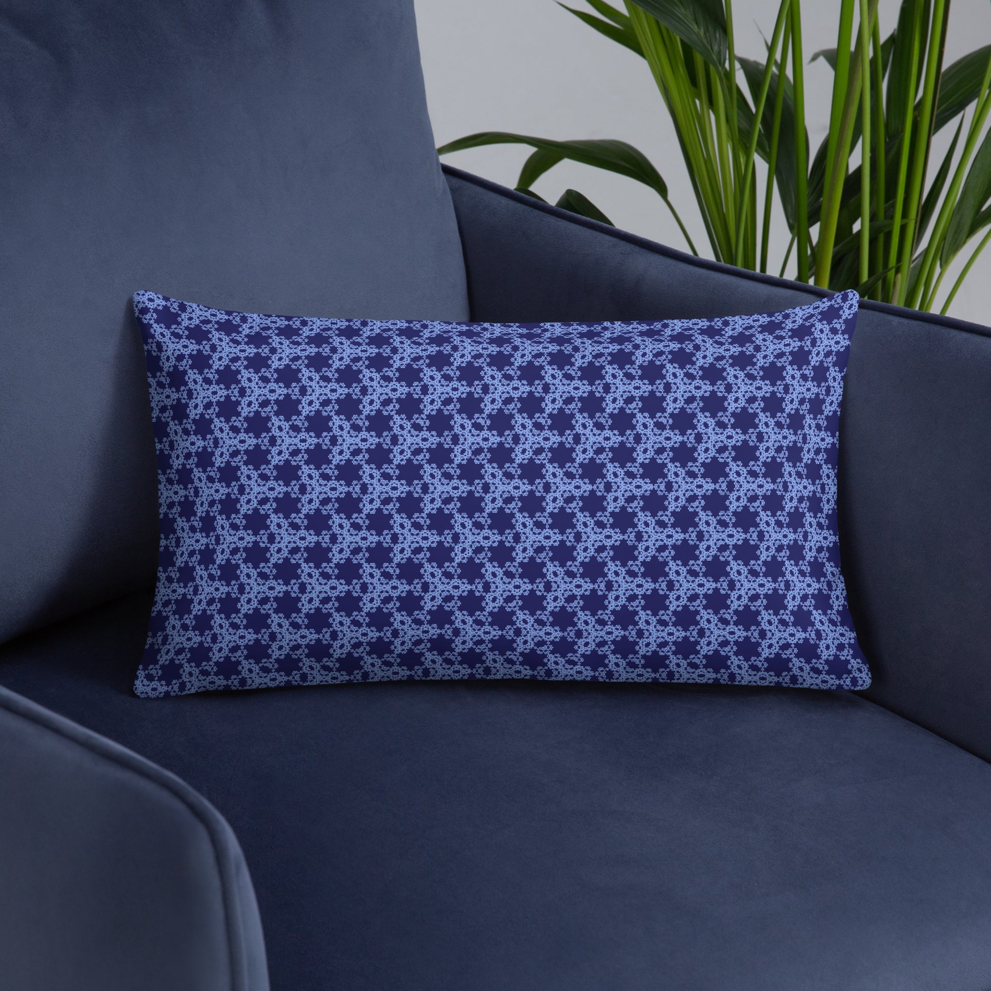20″×12″ throw pillow with the 'Trigon' navy and blue geometric pattern on an armchair.