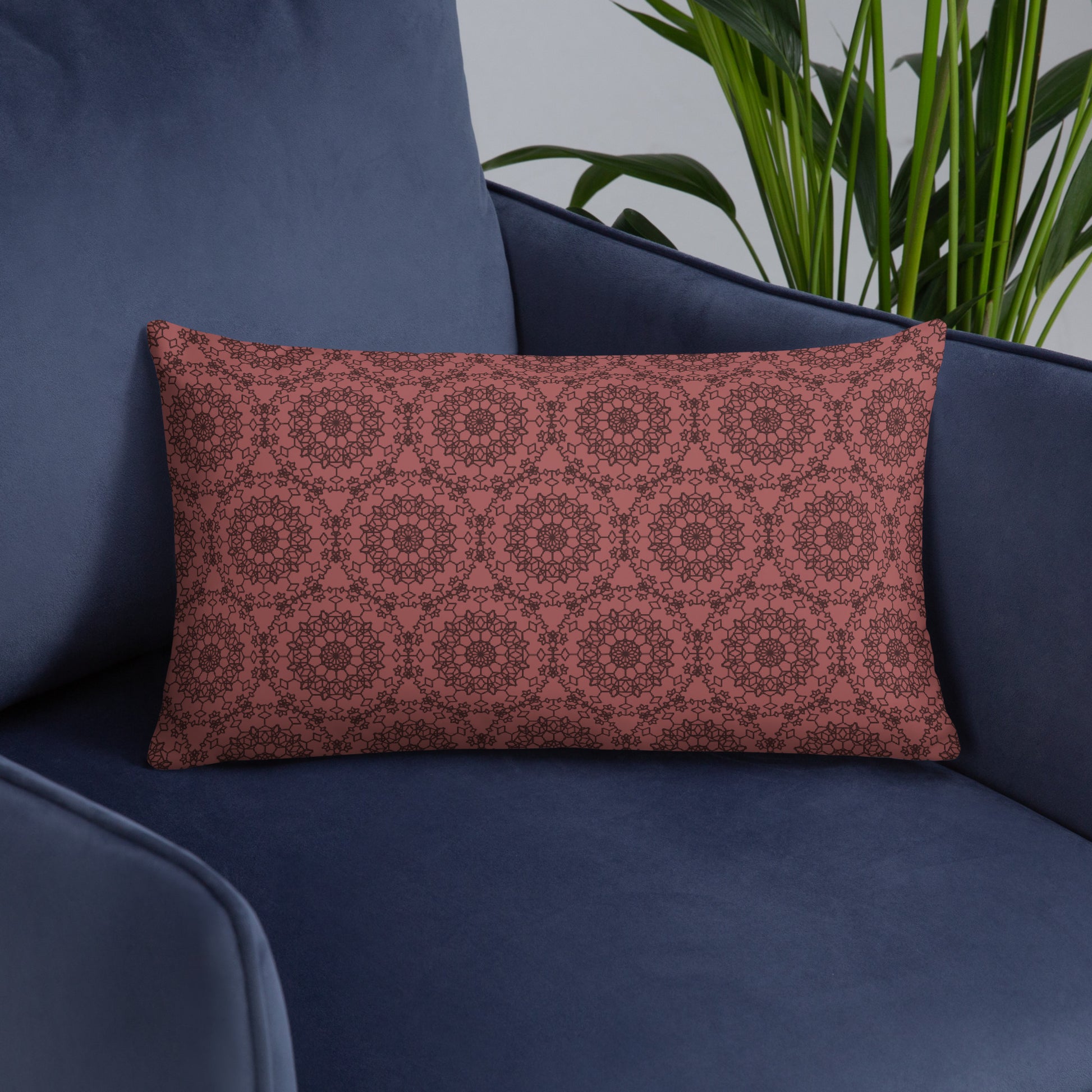 20″×12″ throw pillow with the 'Dodecagon' rose geometric pattern on navy blue armchair.