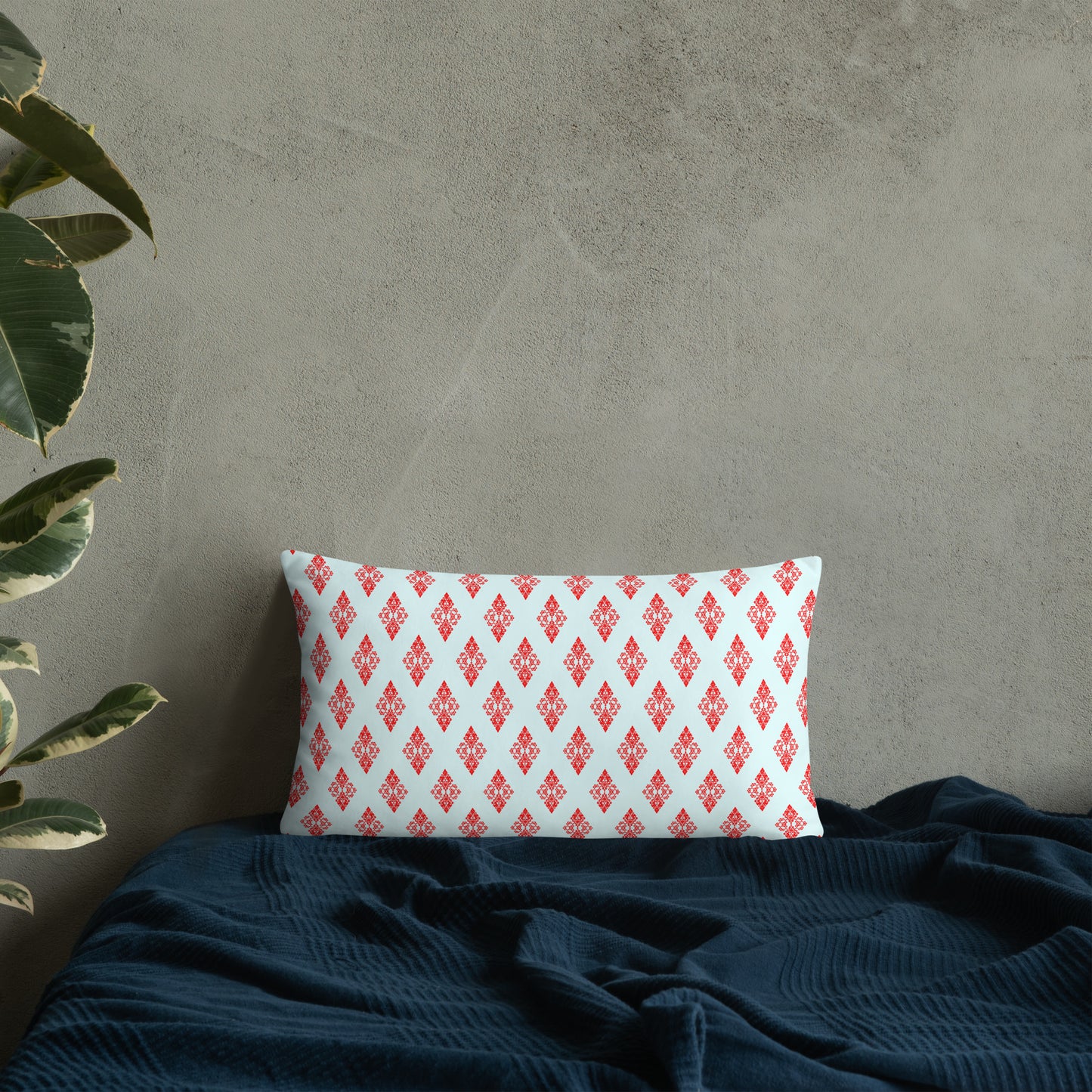 20″×12″ throw pillow with the 'Digon' sky blue and red geometric pattern on a bed.