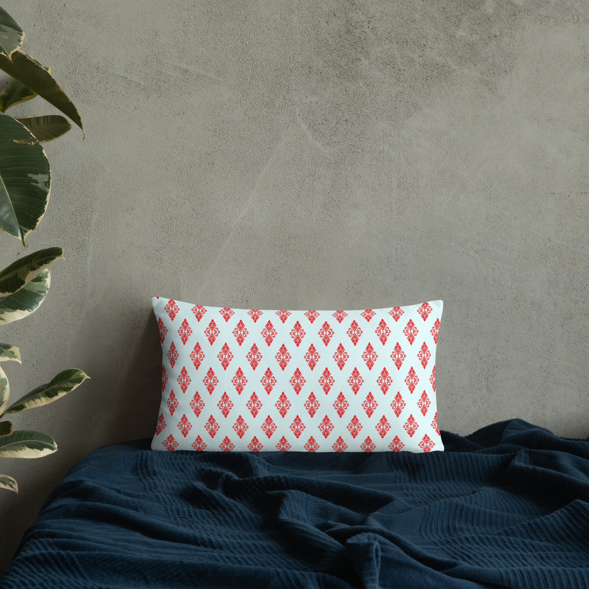 20″×12″ throw pillow with the 'Digon' sky blue and red geometric pattern on a bed.