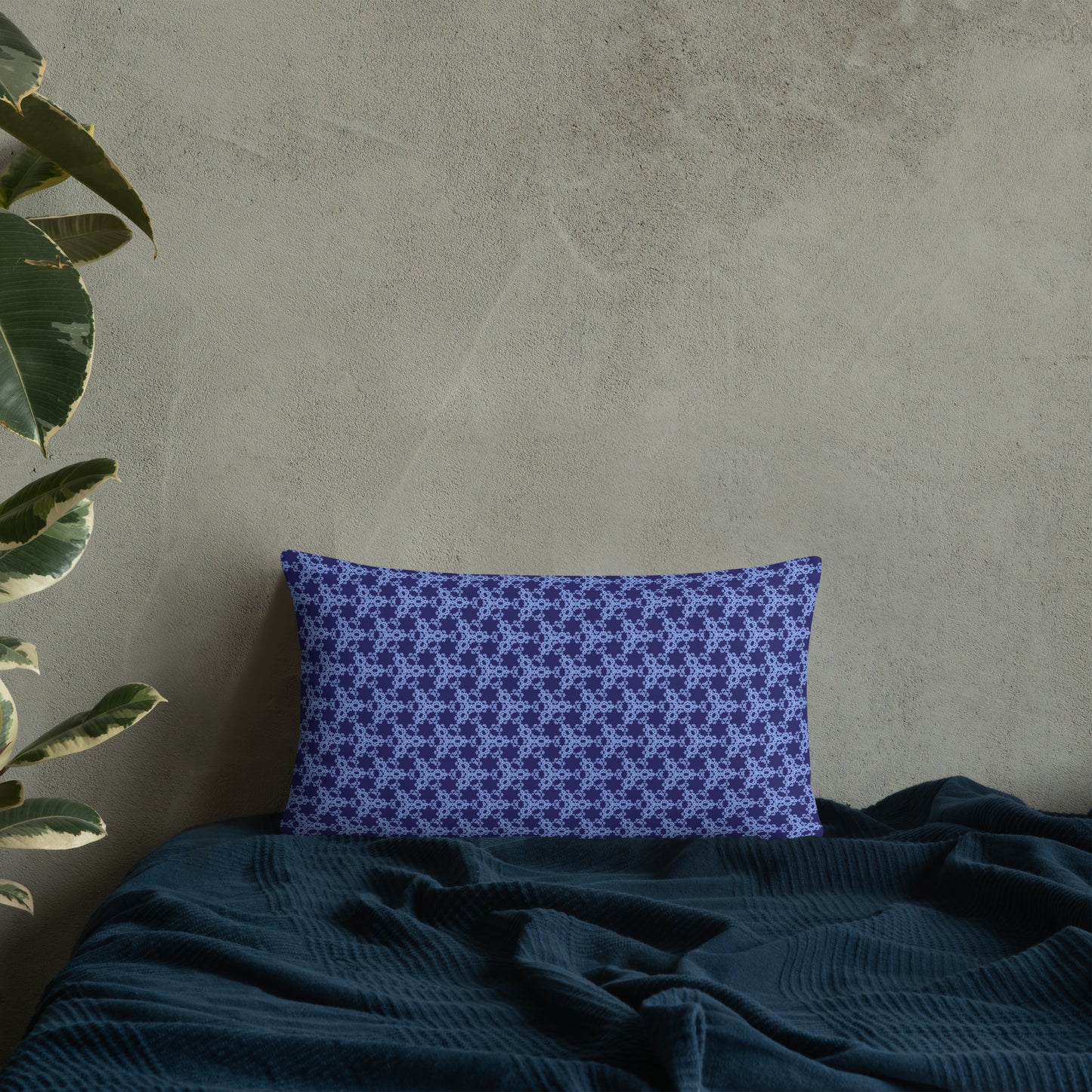 20″×12″ throw pillow with the 'Trigon' navy and blue geometric pattern on a bed.