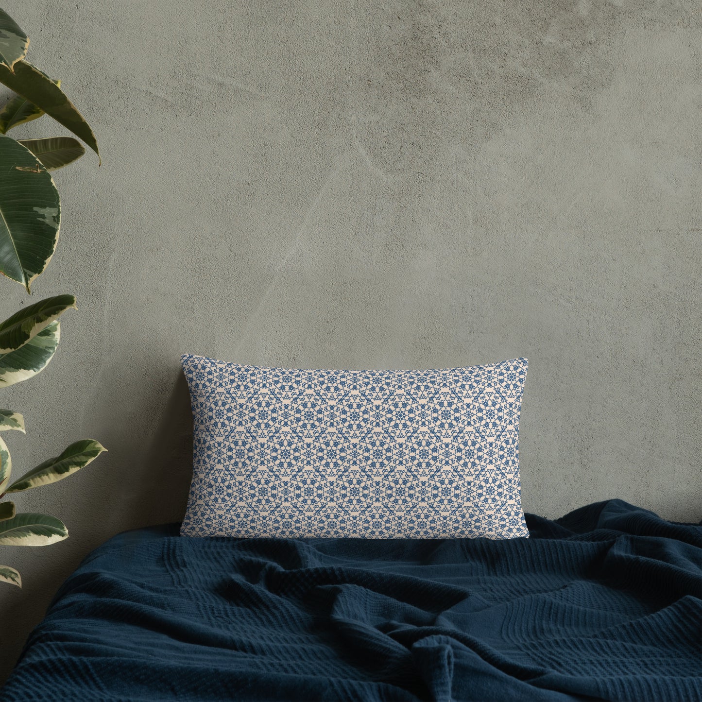 20″×12″ throw pillow with the ‘Octagon’ navy and beige geometric pattern on a bed with dark blanket.
