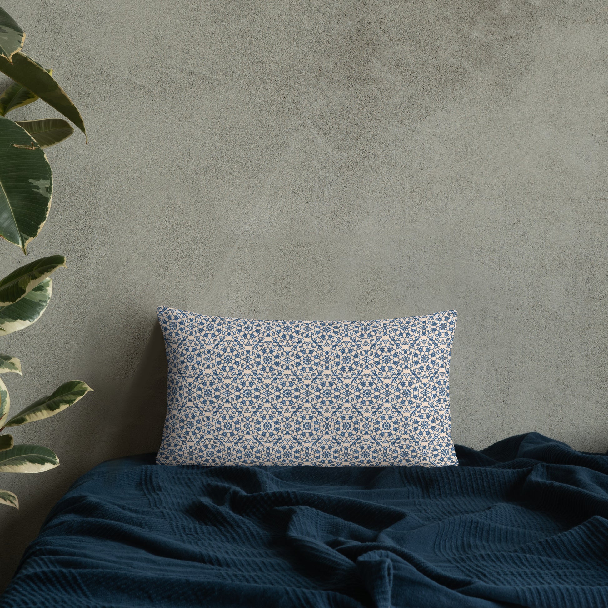 20″×12″ throw pillow with the ‘Octagon’ navy and beige geometric pattern on a bed with dark blanket.