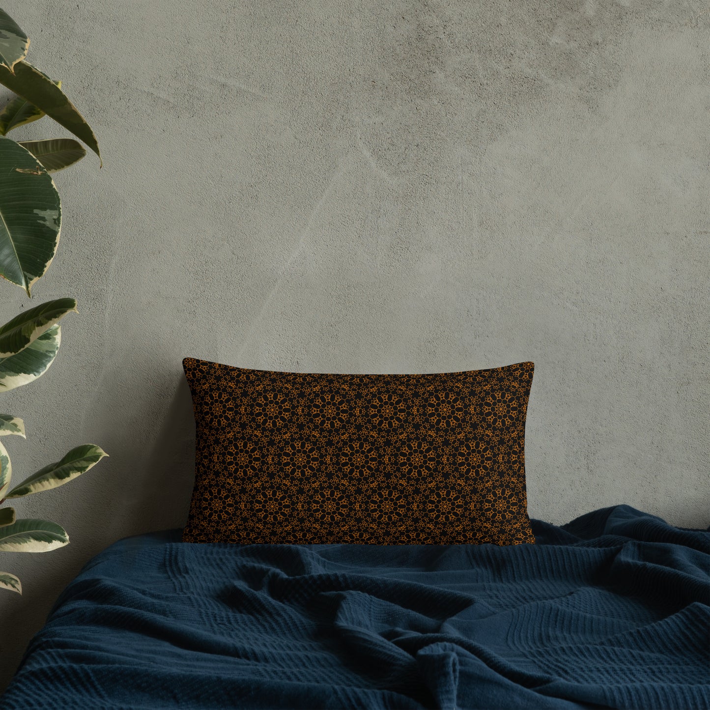 20″×12″ throw pillow with the 'Enneagon' black & gold geometric pattern on a bed with dark teal blanket.